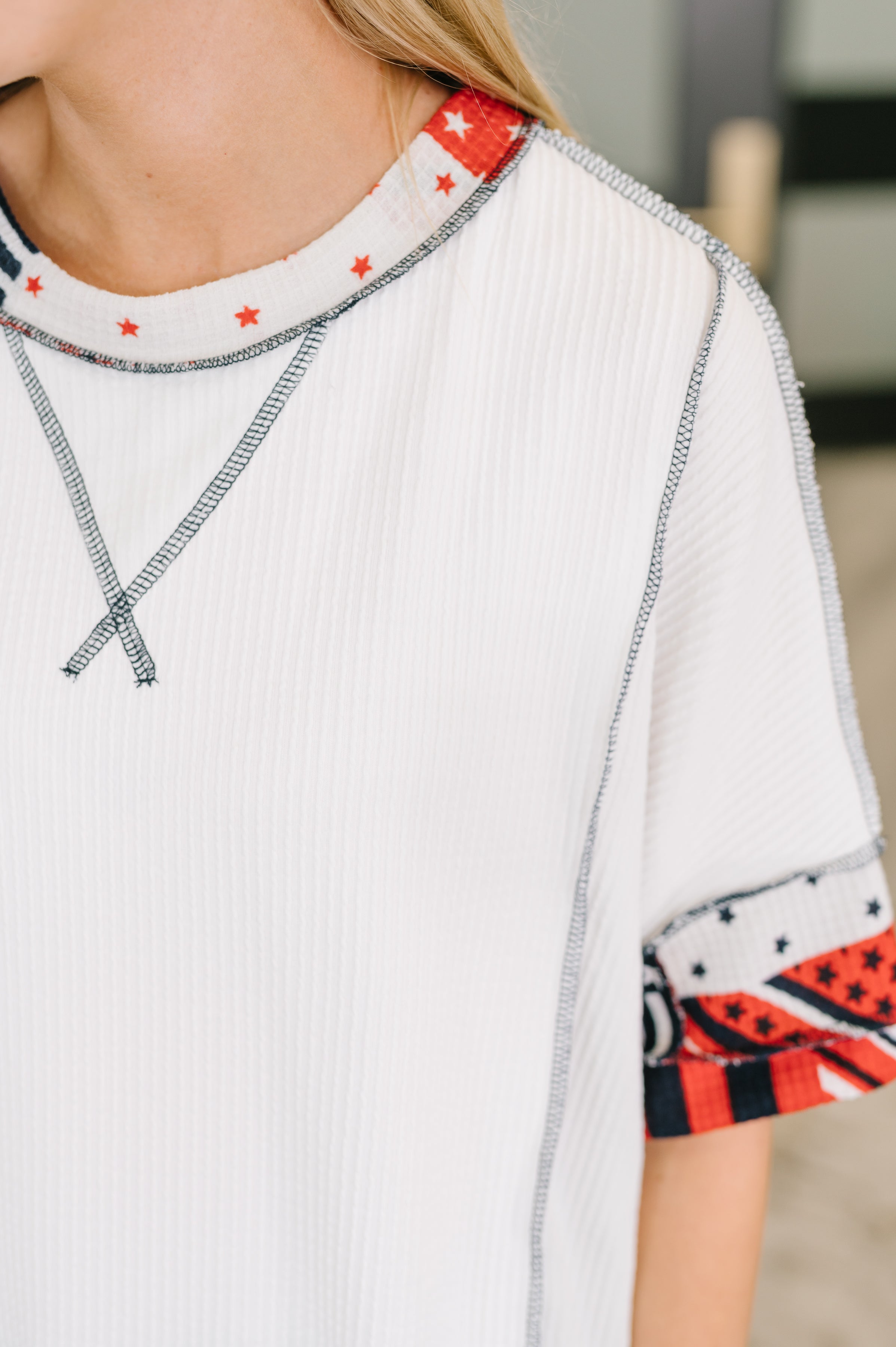 Close-up of cream cable ribbed top with red and navy patchwork details and contrast stitching in eclectic style
