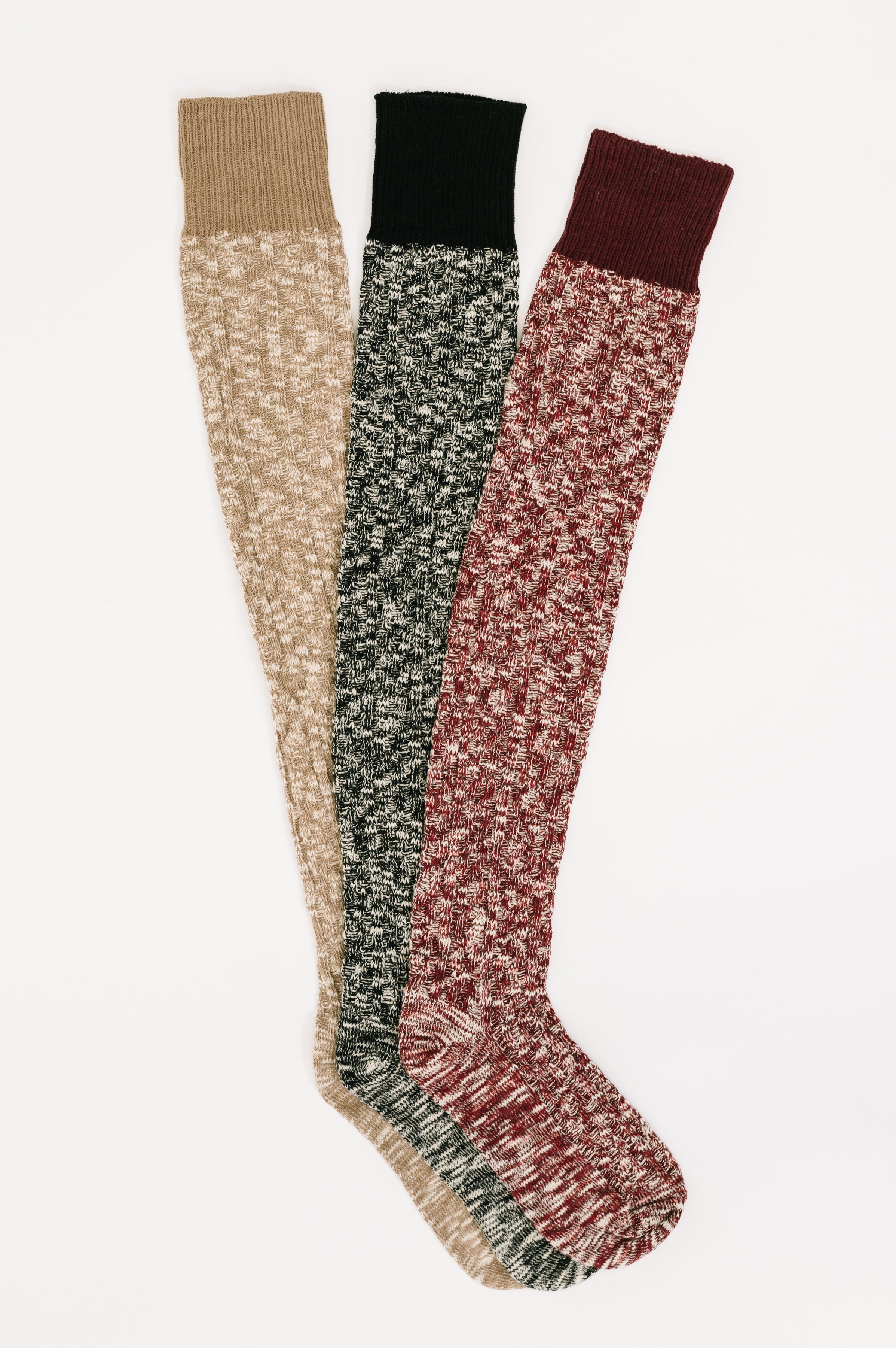Set of three multi-colored knit lounge socks with ribbed cuffs in beige, black, and deep red hues laid flat on white background
