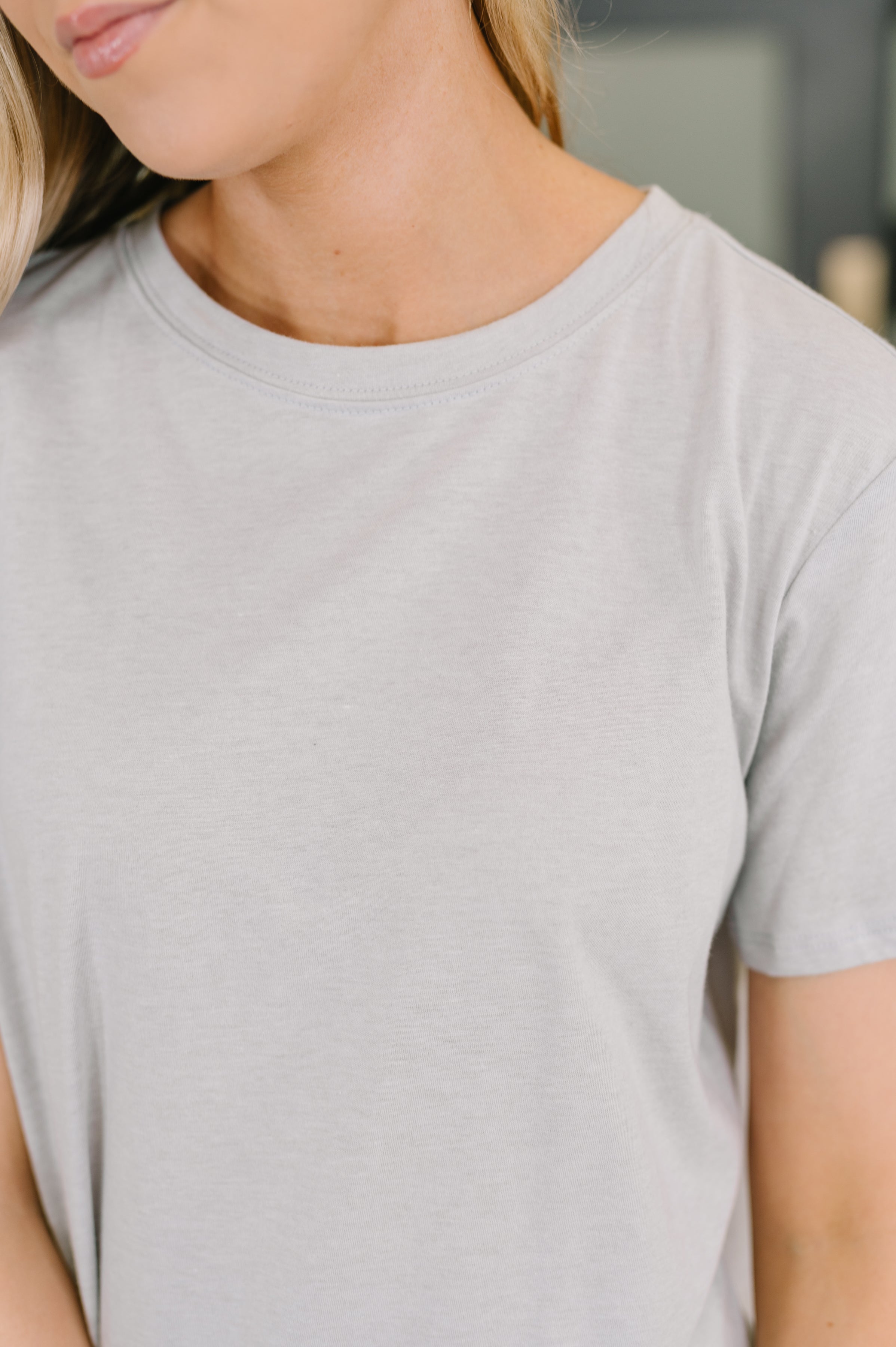 Close-up of a soft heather grey relaxed fit tee with short sleeves on a person in casual setting