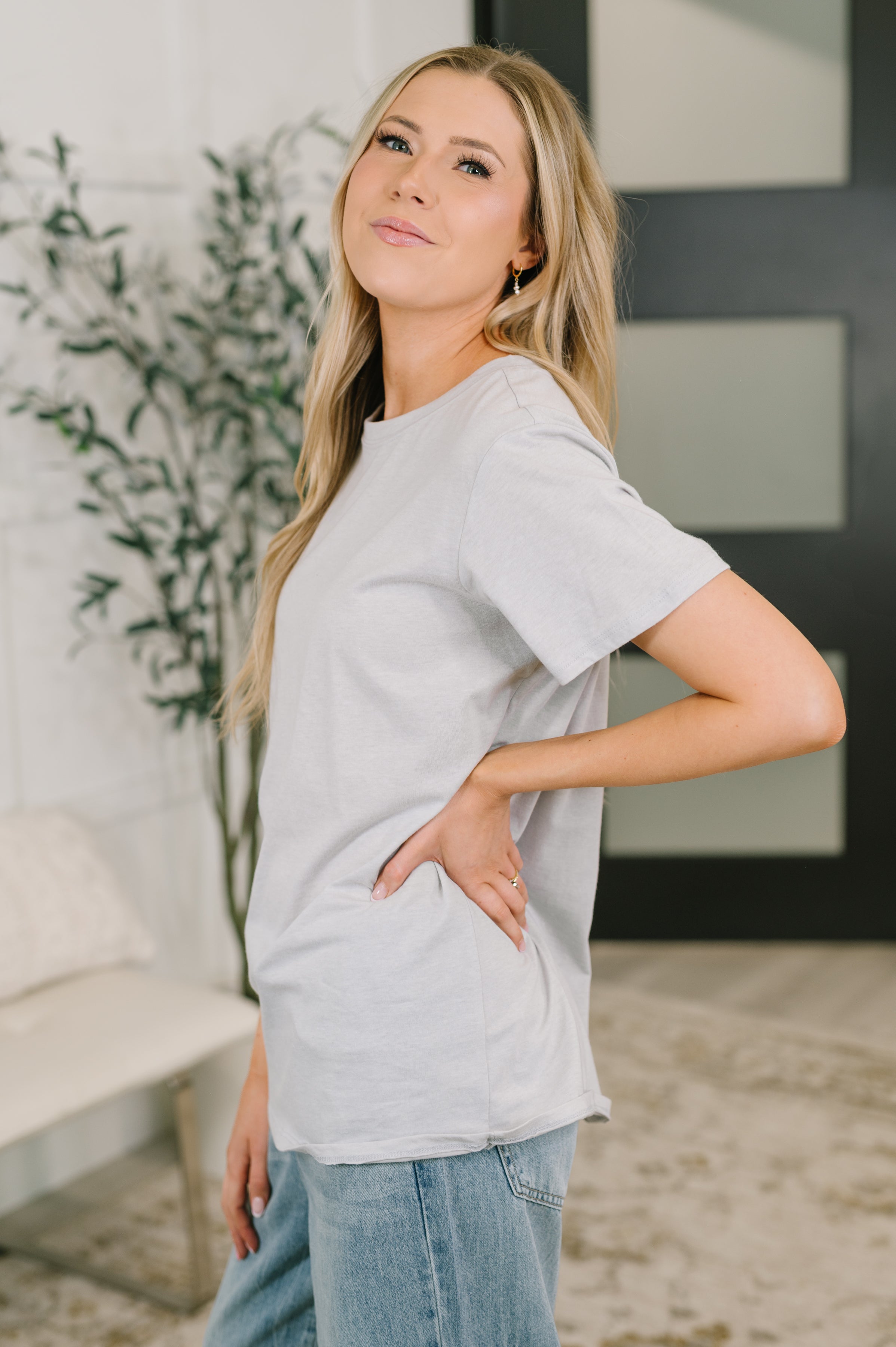Woman wearing soft heather grey relaxed tee paired with light blue jeans in casual indoor setting