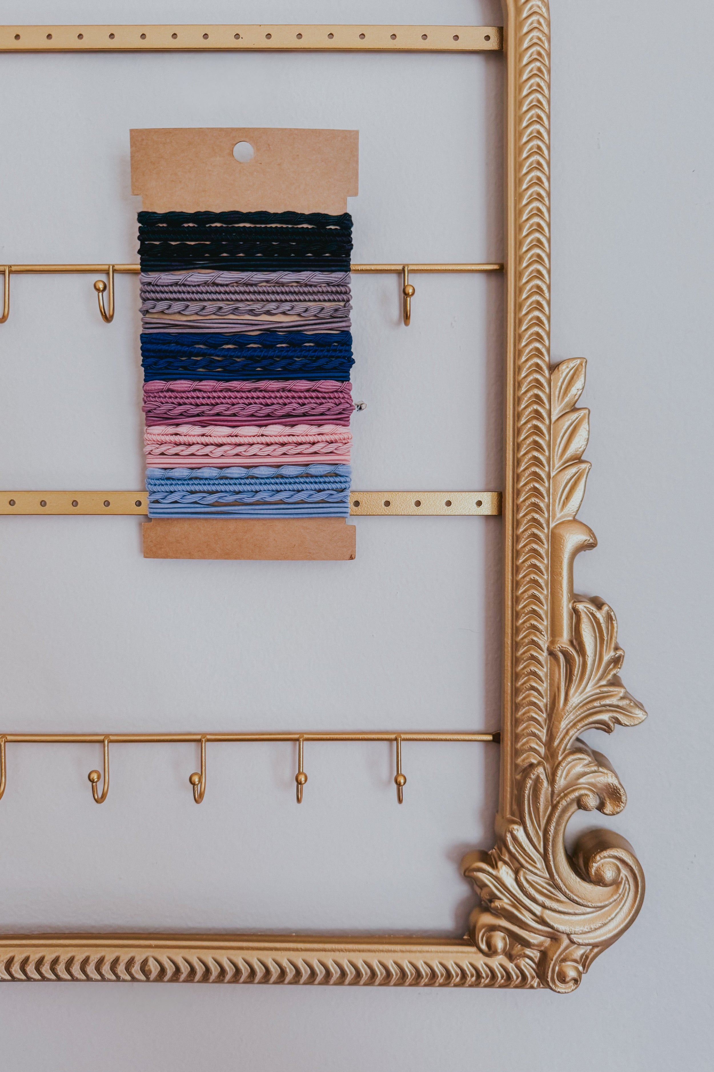 Varied textured hair tie bracelets in night sky hues from deep black to soft blue on kraft card within ornate gold frame