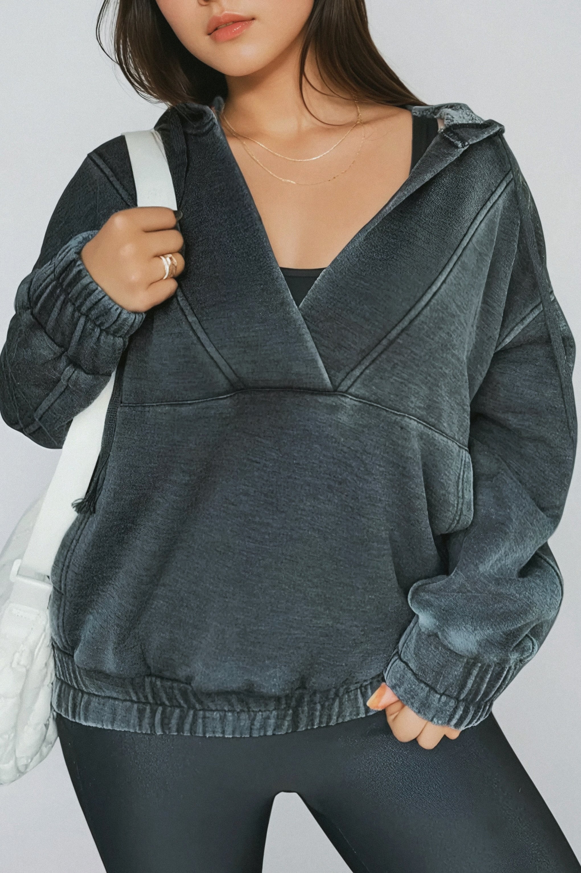 Woman wearing charcoal acid wash hoodie with elastic cuffs and hem paired with black leggings and layered necklaces
