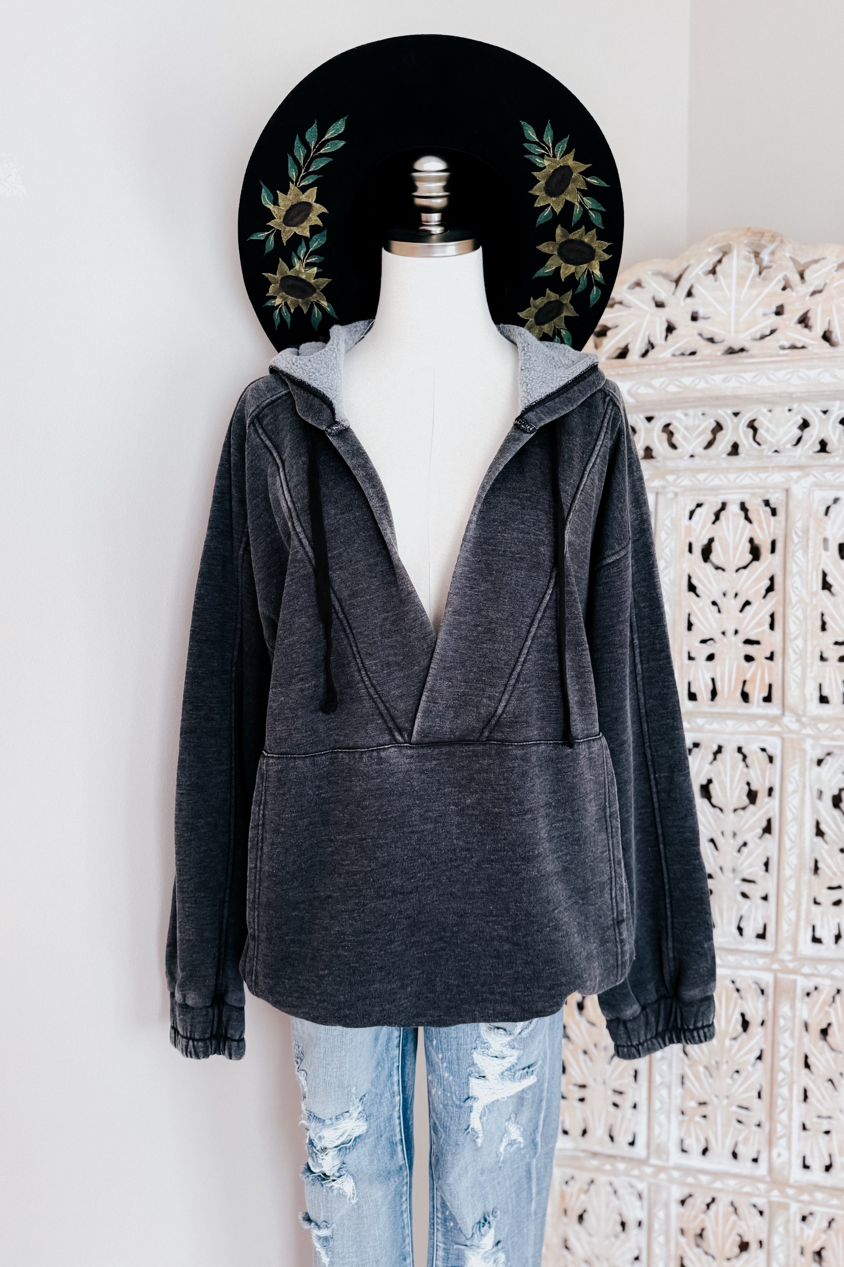 Charcoal acid wash hoodie with drawstrings and front pocket styled on mannequin with distressed light blue jeans