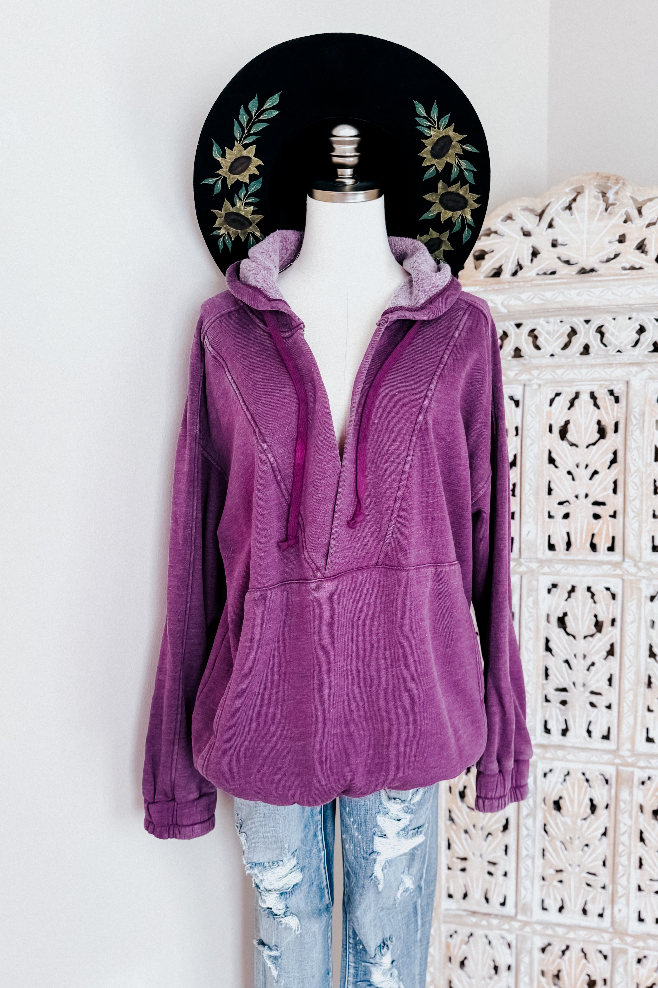 Plum acid wash hoodie with plush-lined hood and drawstrings displayed on mannequin with distressed jeans and decorative hat