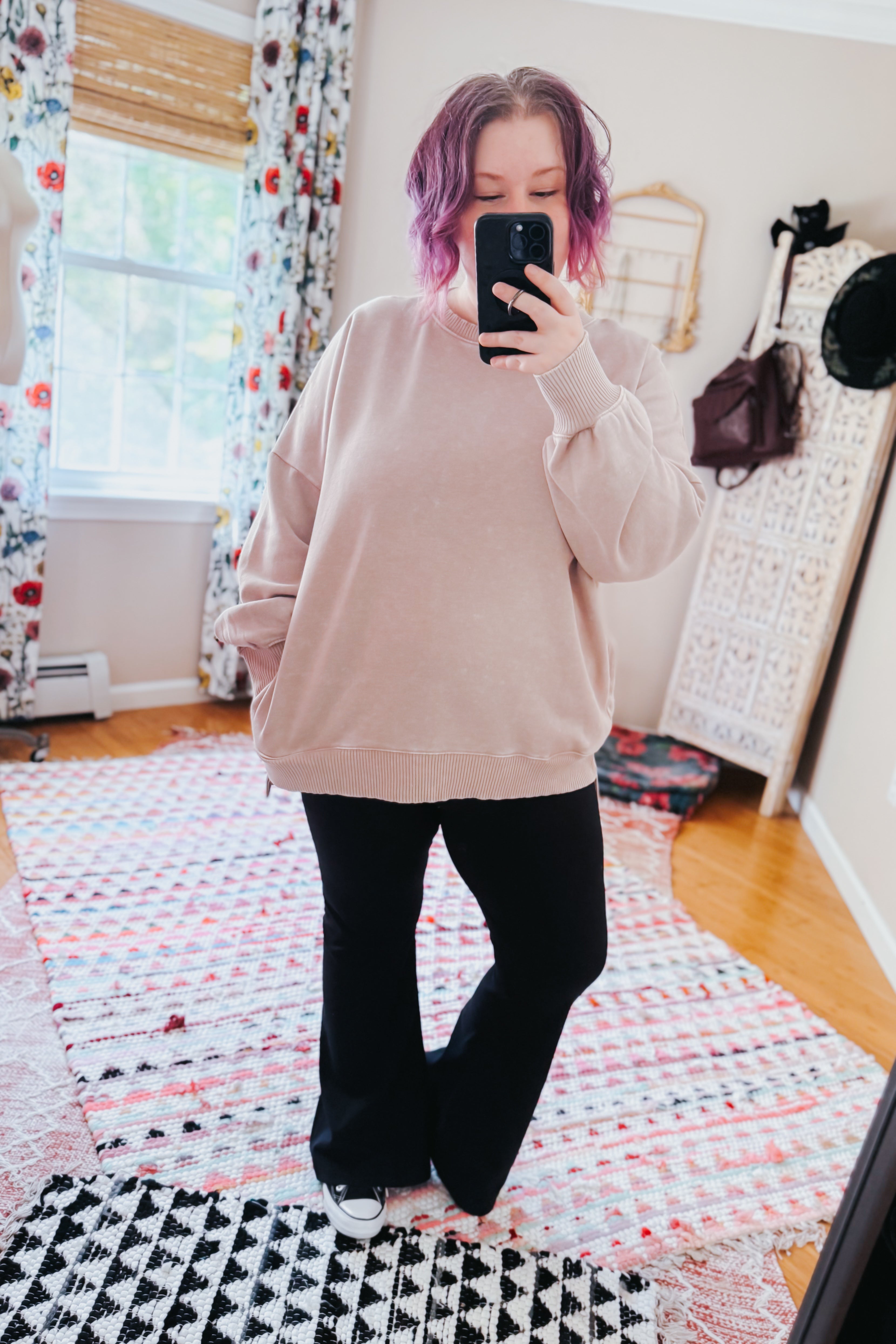 Woman with purple hair wearing oversized ash mocha mineral wash pullover and black pants taking mirror selfie indoors
