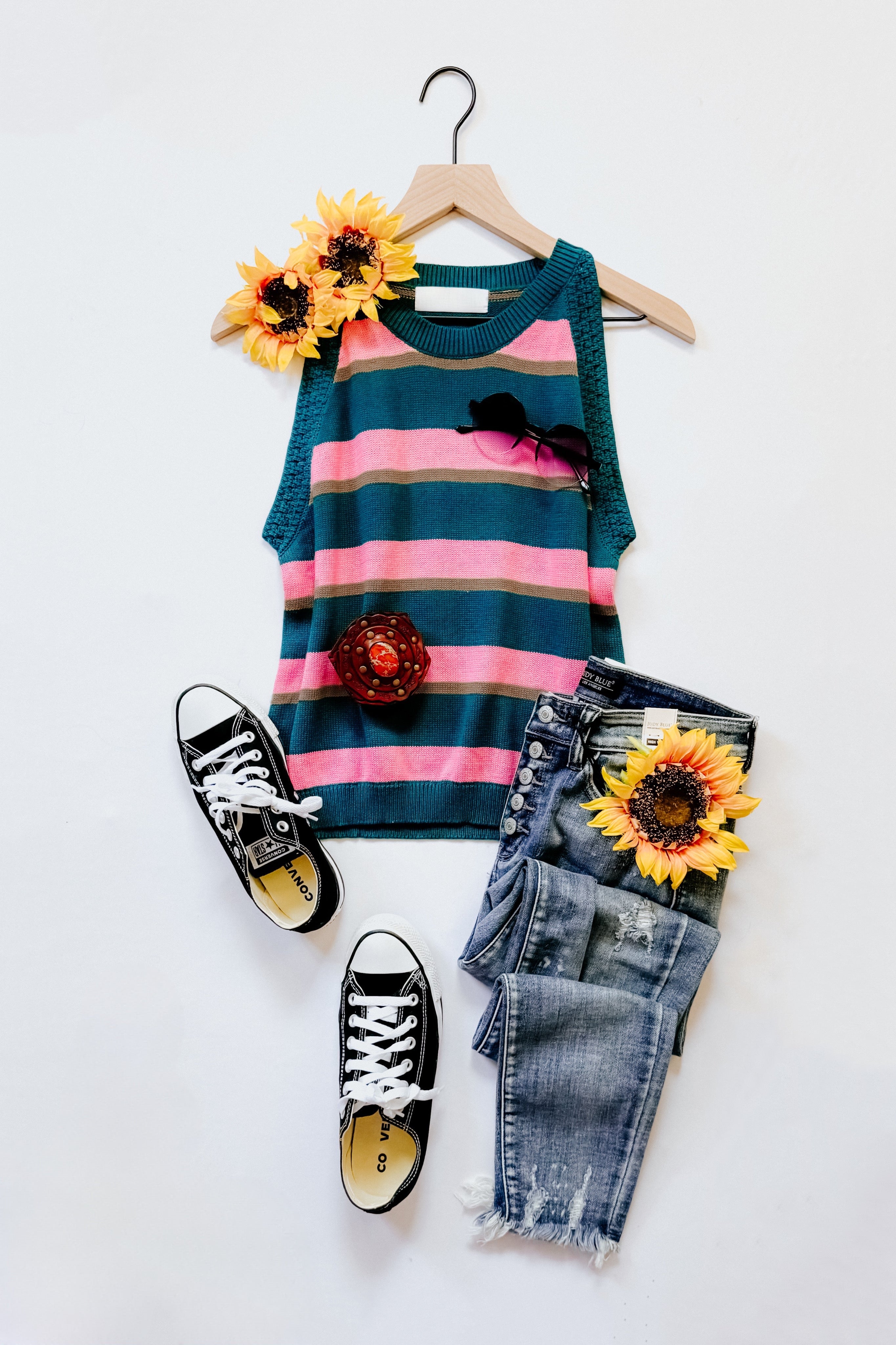 Knit striped tank in blue and pink with distressed blue jeans, black sneakers, and sunflower accents styled on white background