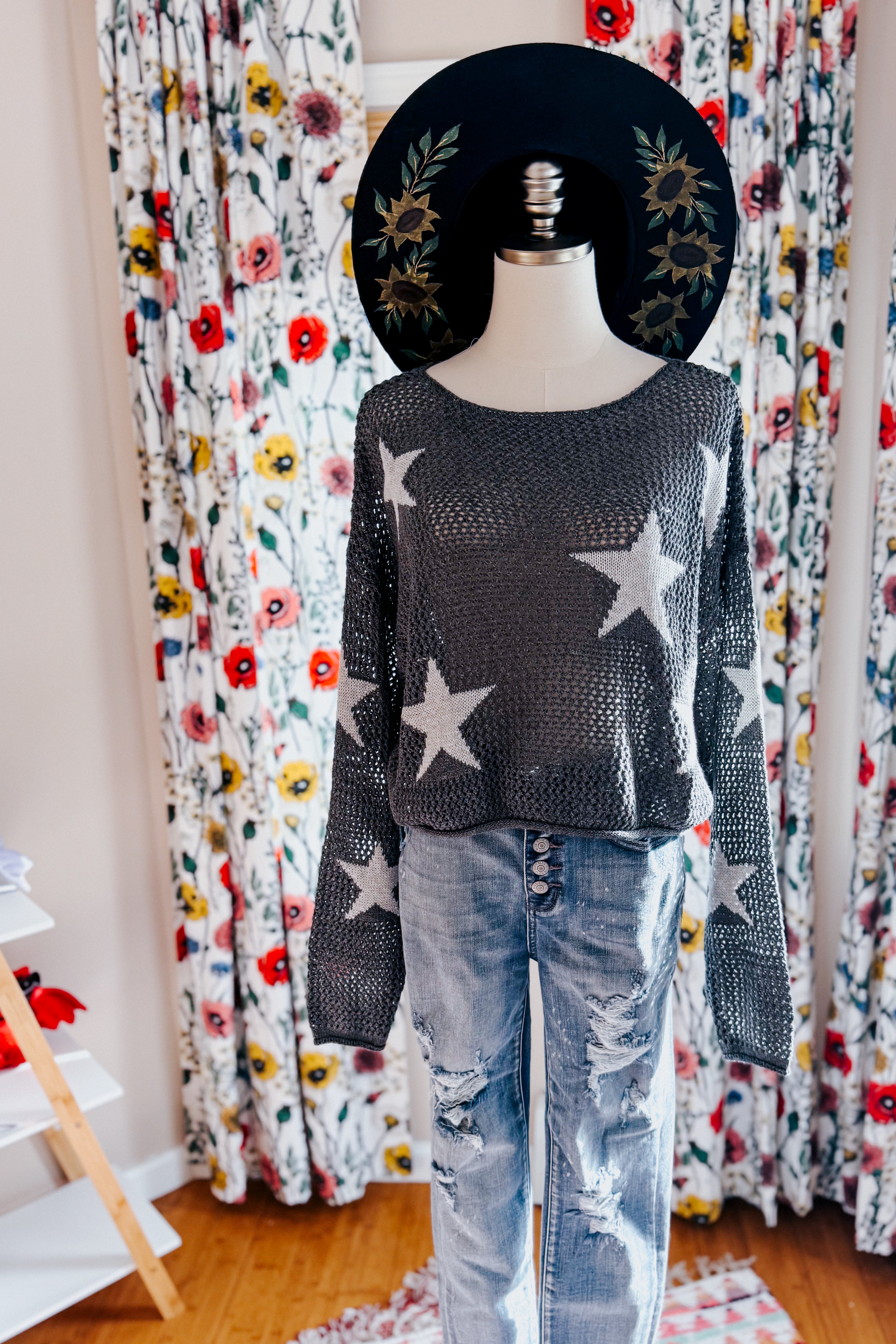 Charcoal mesh sweater with white star pattern paired with distressed light wash jeans and embroidered black hat