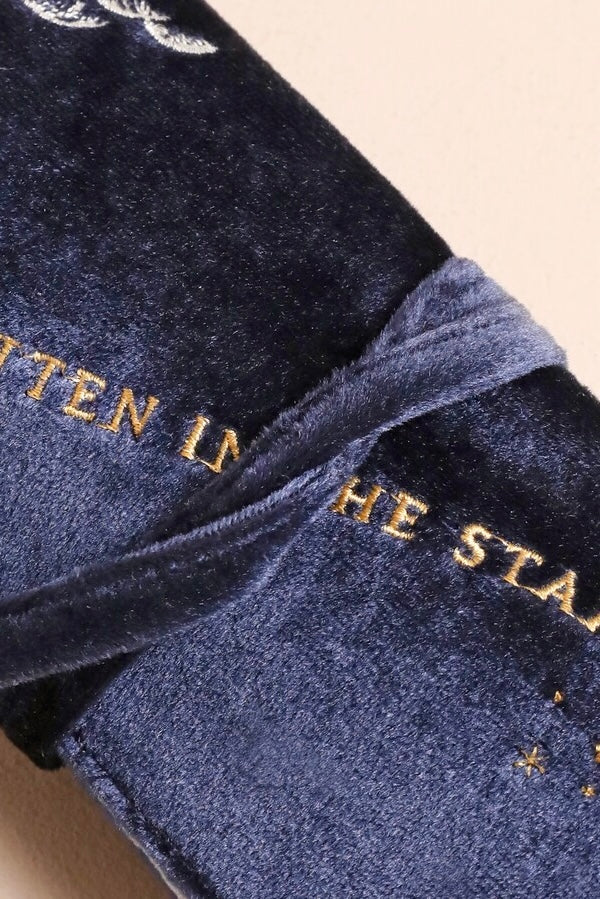Close-up of plush navy velvet jewelry roll with gold celestial embroidery and soft velvet tie closure