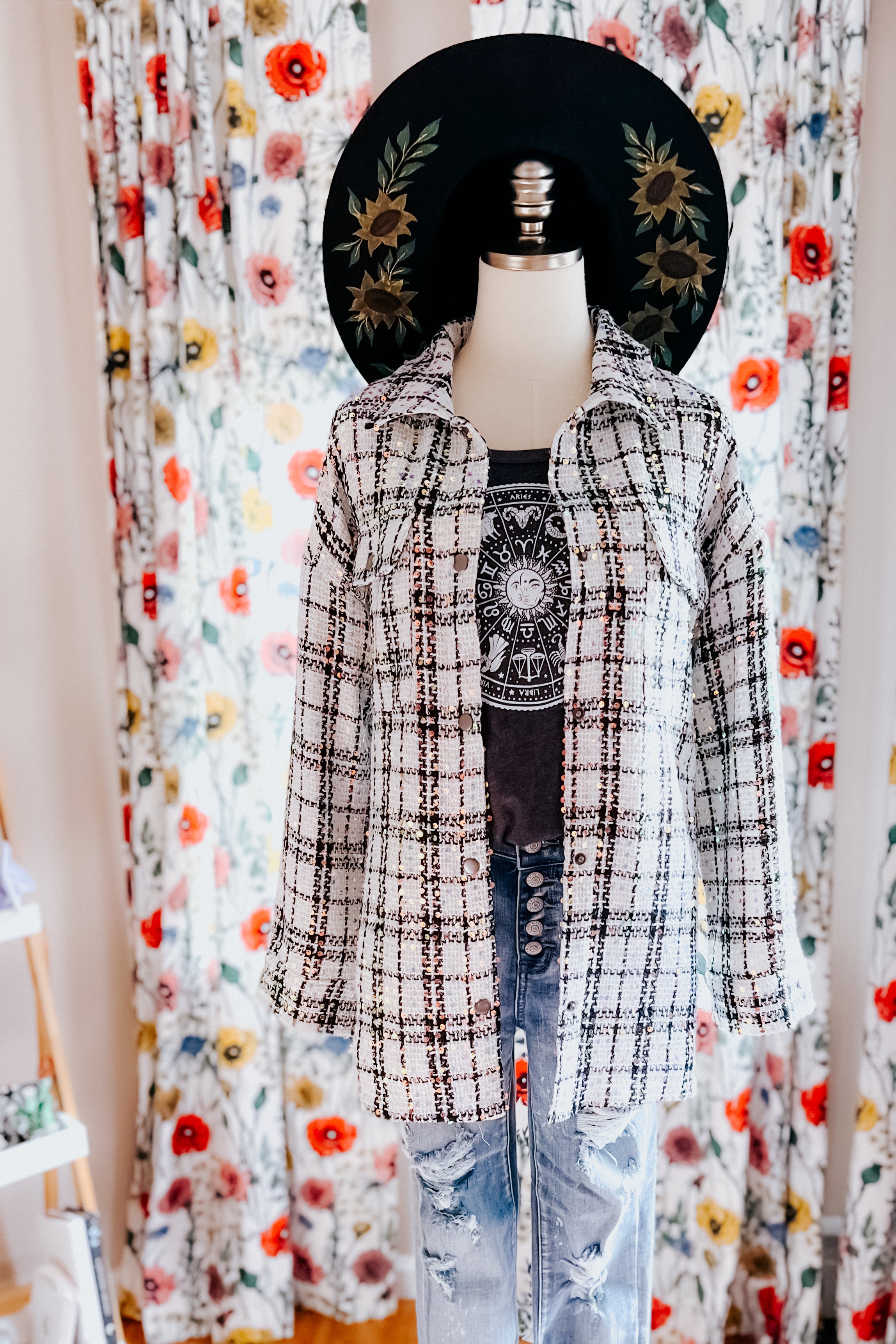White plaid sequin shacket styled with graphic tee, distressed blue jeans, and black hat with sunflower designs.