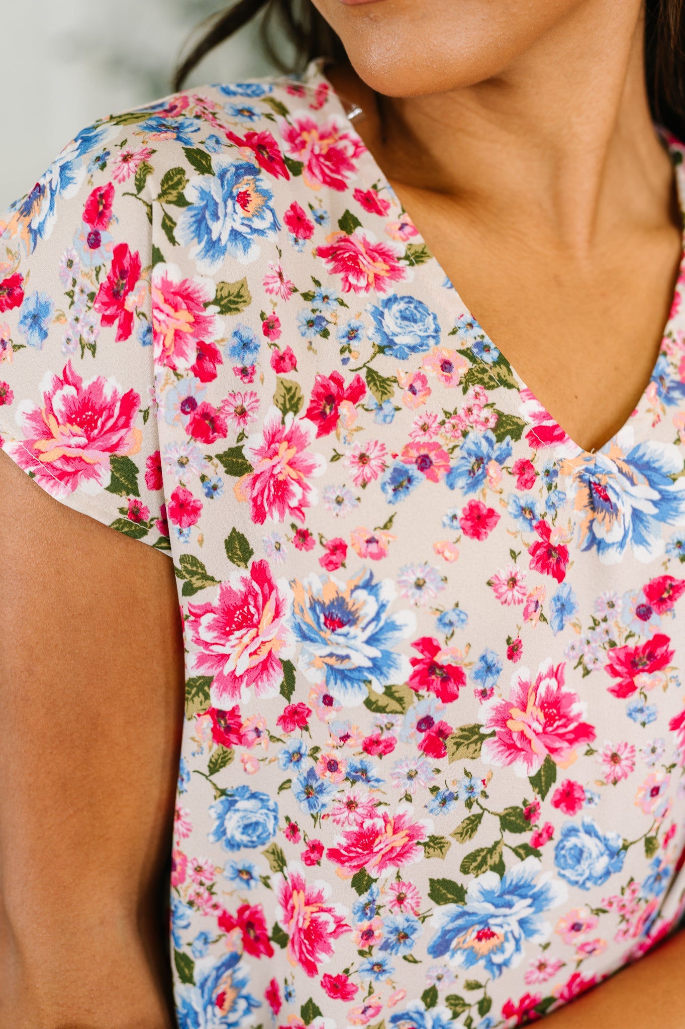Close-up of lightweight pink fabric with vibrant blue and red floral print on a feminine blouse neckline and sleeve
