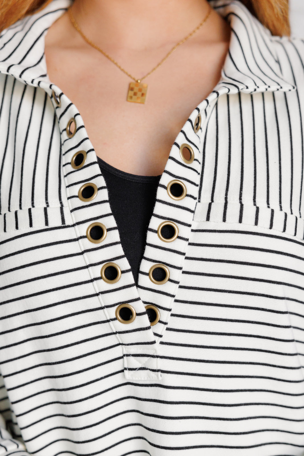 Woman wearing a white and black striped collared pullover top.