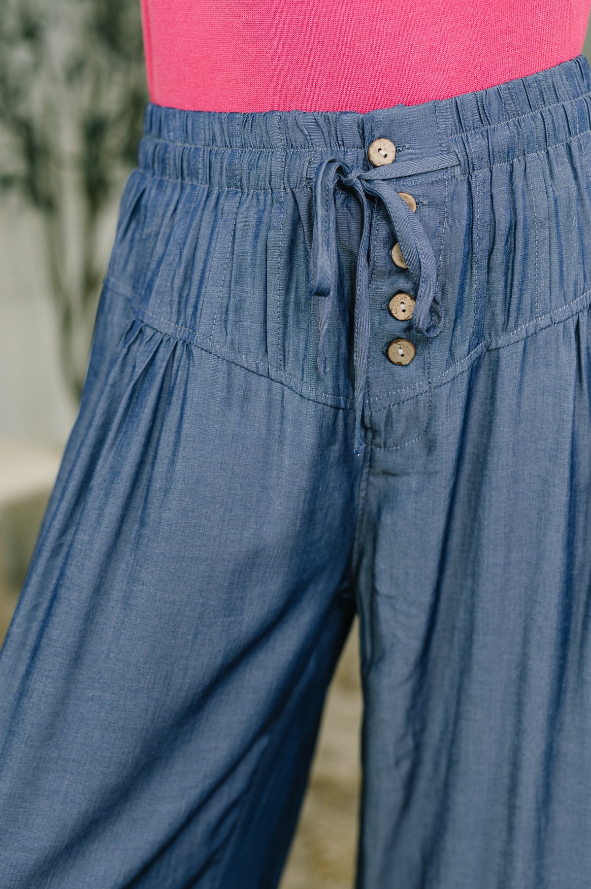 Blue high waisted wide leg bottoms with a drawstring waist and button front detail styled with a pink top