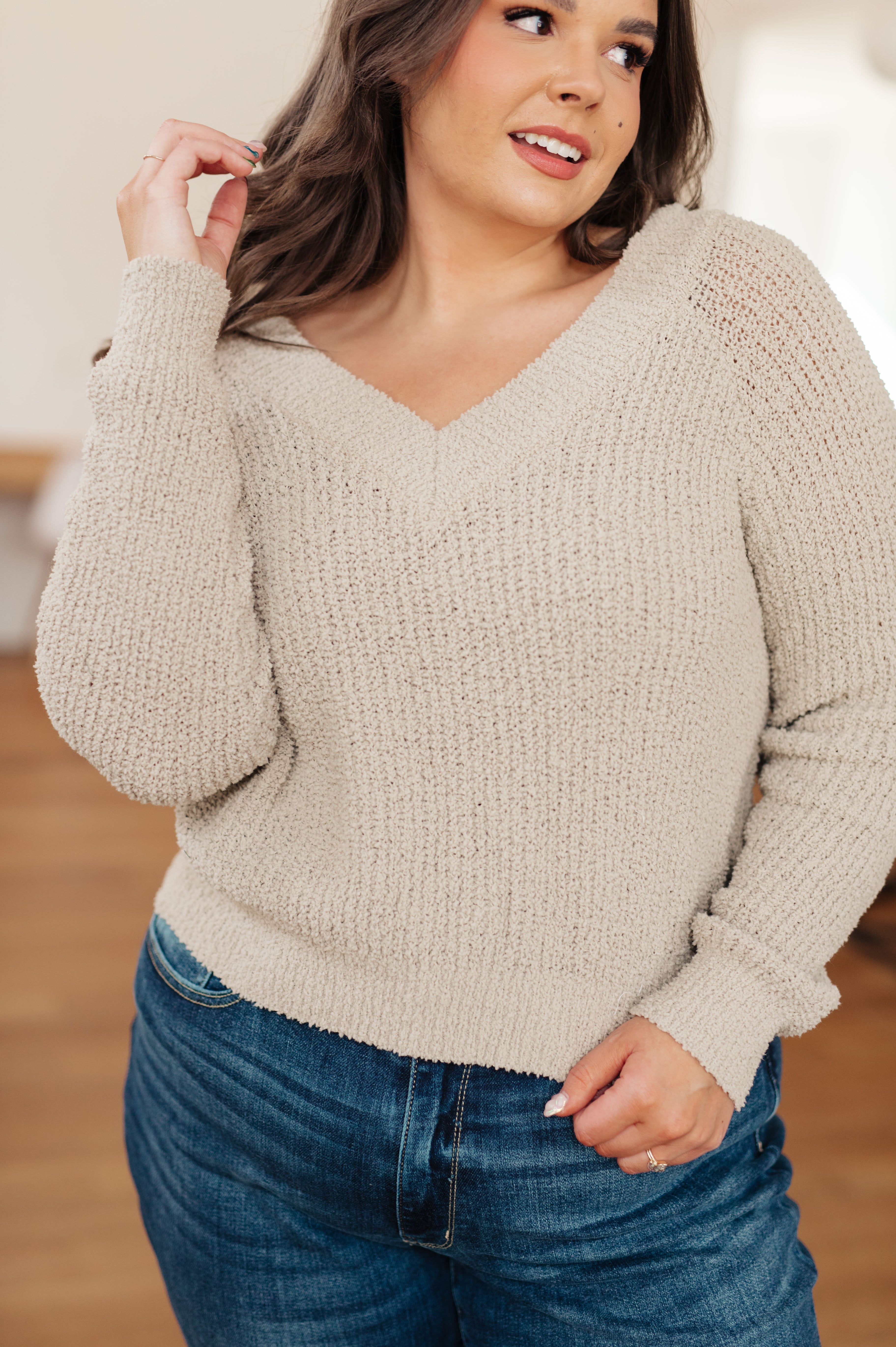 Curvy woman wearing beige textured V-neck sweater with cozy knit fabric and long sleeves indoors