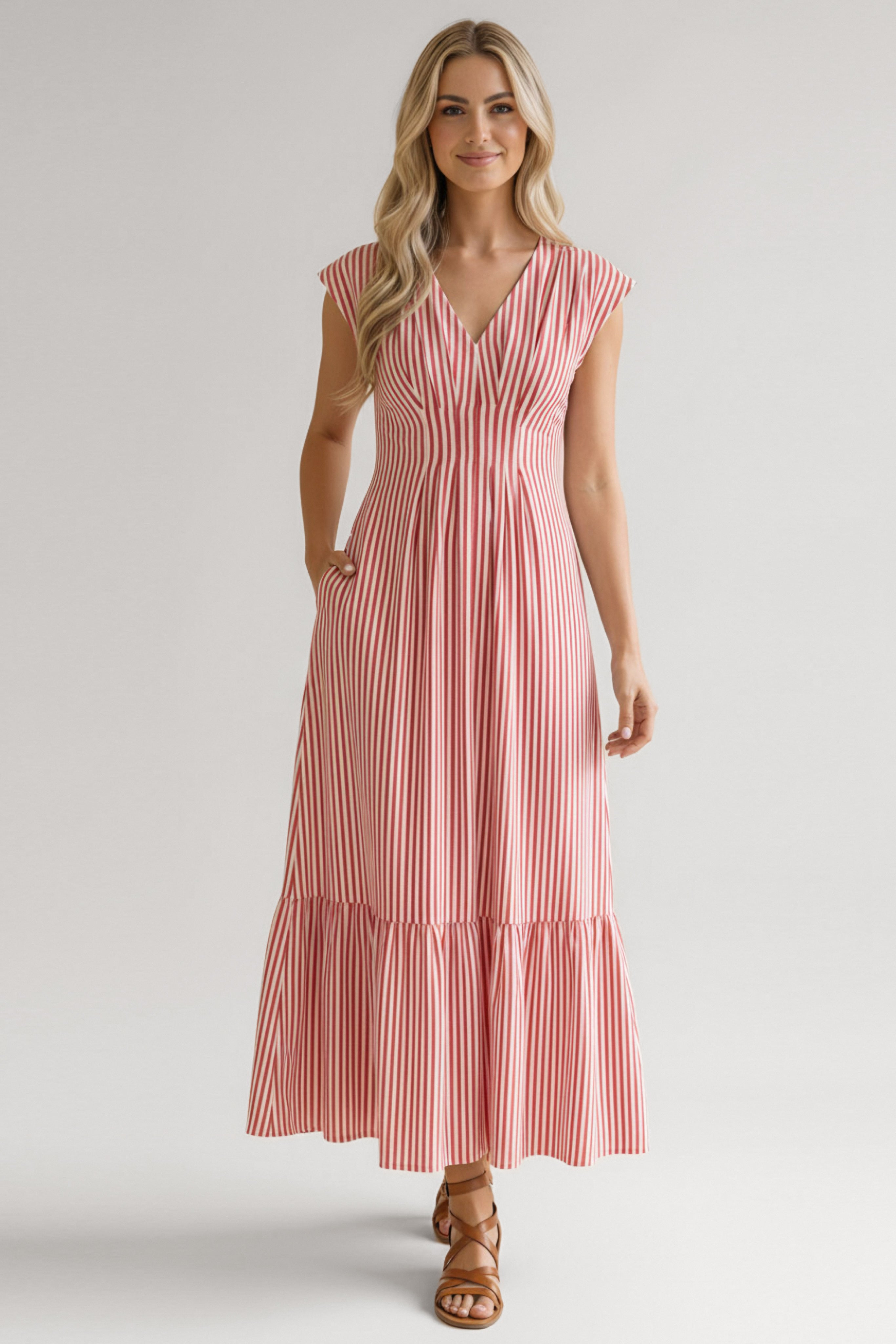 Woman wearing red striped tiered maxi dress with v-neck and cap sleeves paired with brown lace-up sandals standing