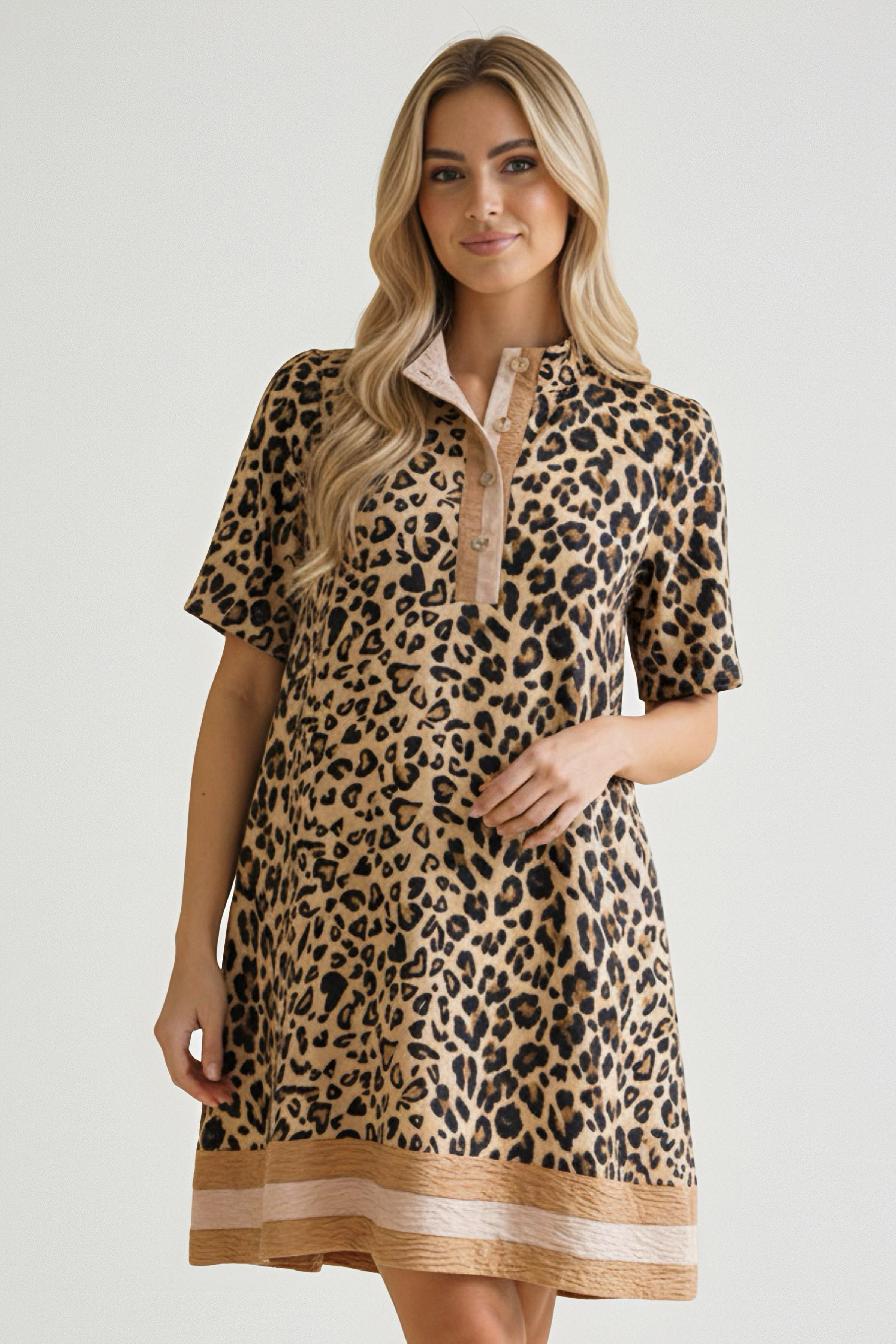 Woman wearing a honey-colored leopard print dress with short sleeves and a buttoned placket standing indoors