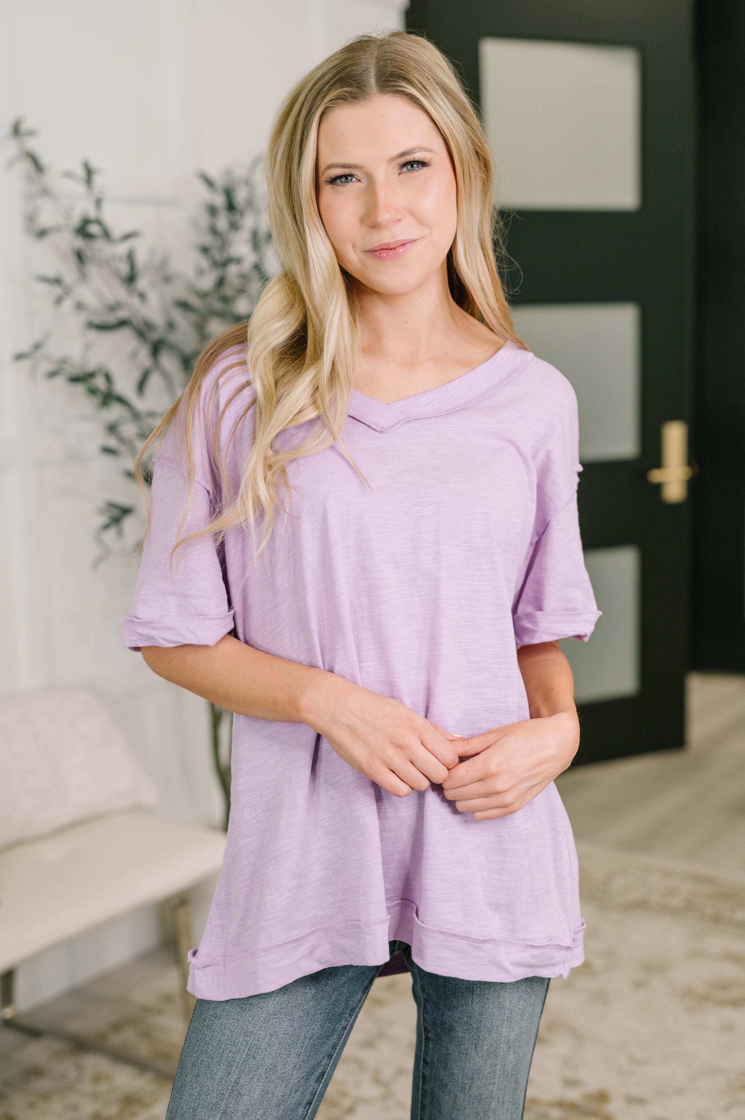 Woman wearing lilac relaxed V-neck tee with rolled sleeves and soft texture paired with casual denim jeans indoors
