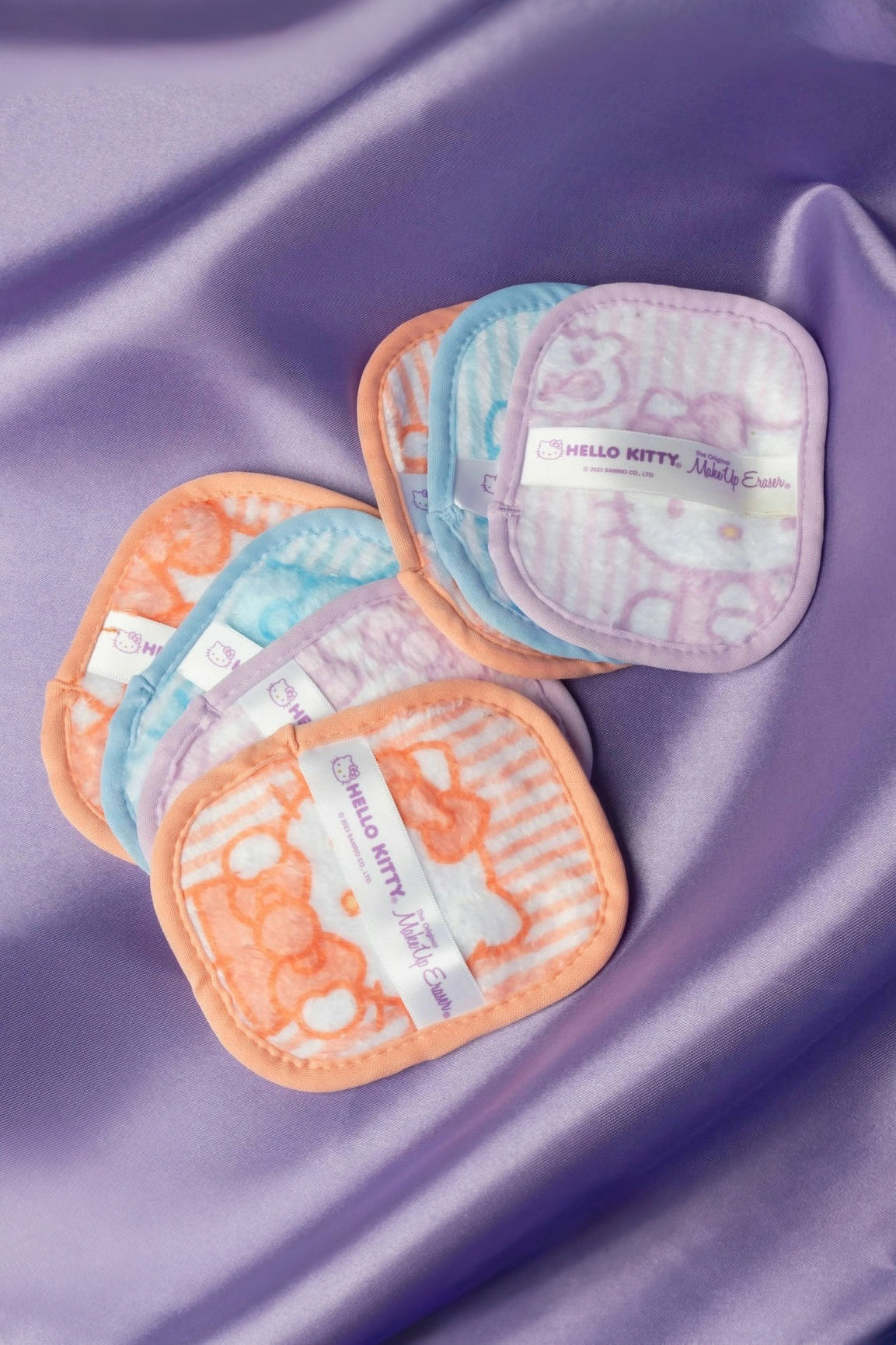 Set of colorful soft makeup remover pads with Hello Kitty design displayed on lavender satin fabric