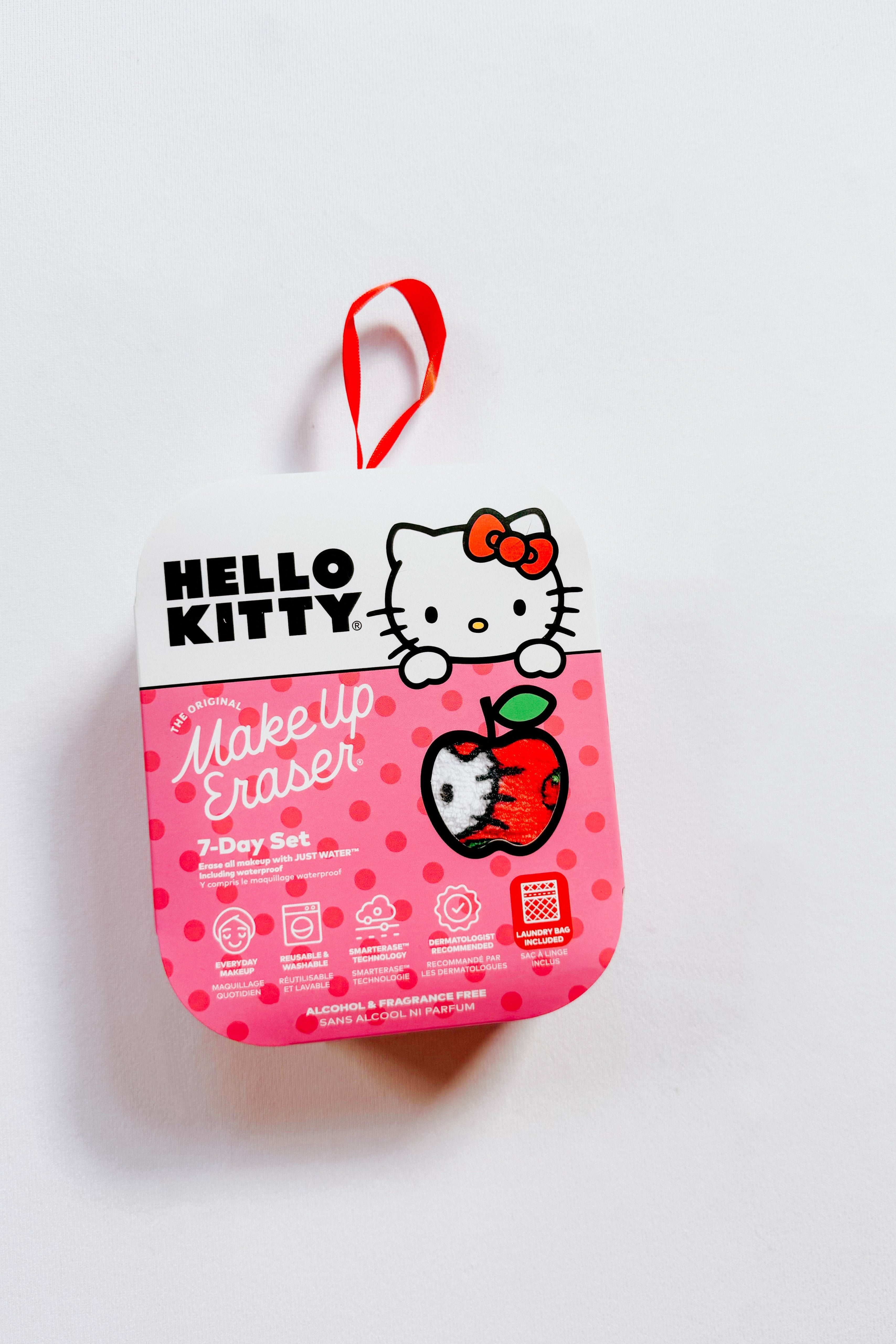Pink Hello Kitty makeup eraser packaging with a red loop handle and an apple graphic on white background