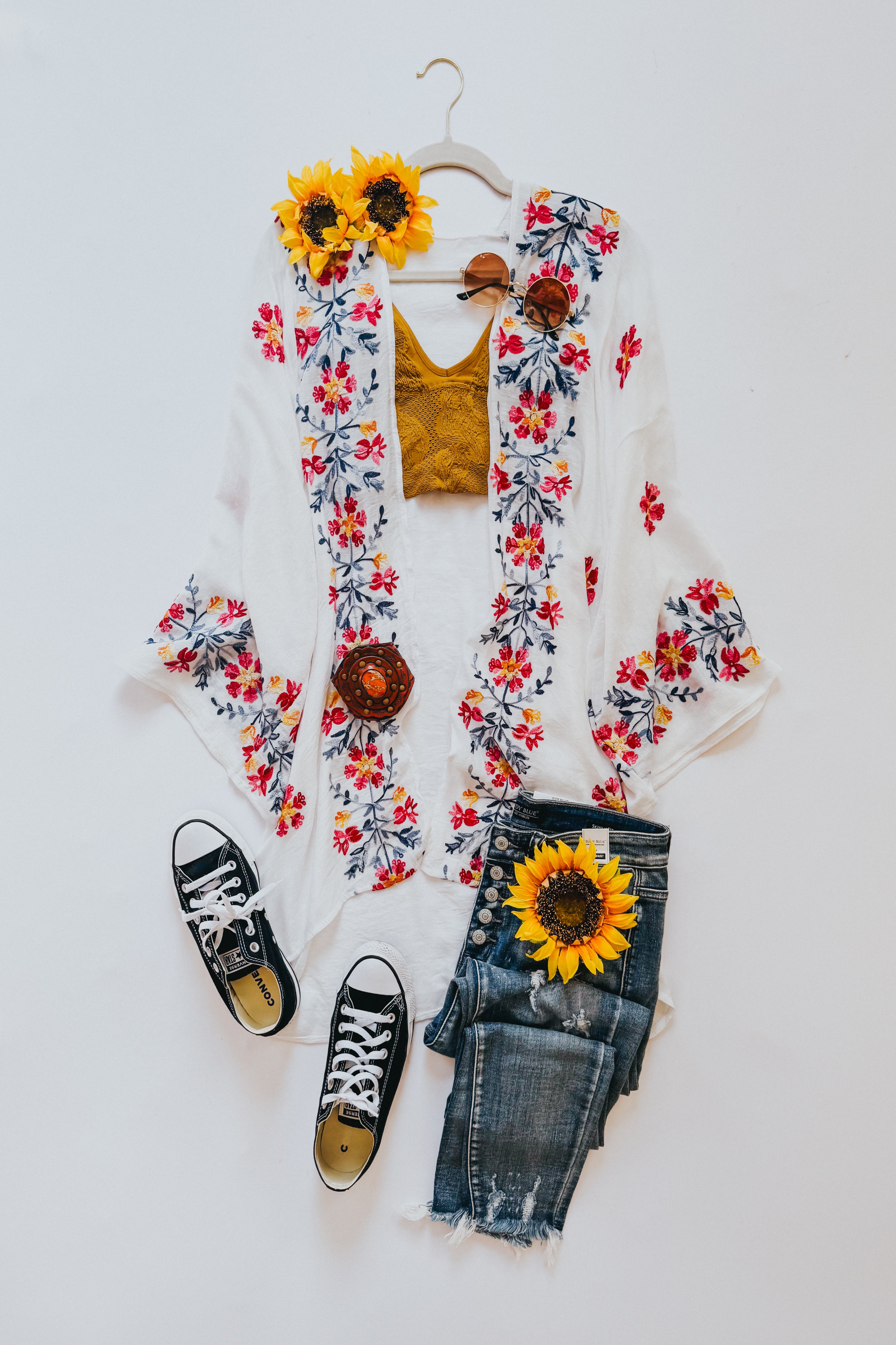 Ivory embroidered duster styled with distressed denim shorts, black sneakers, yellow crop top, and sunflower accessories