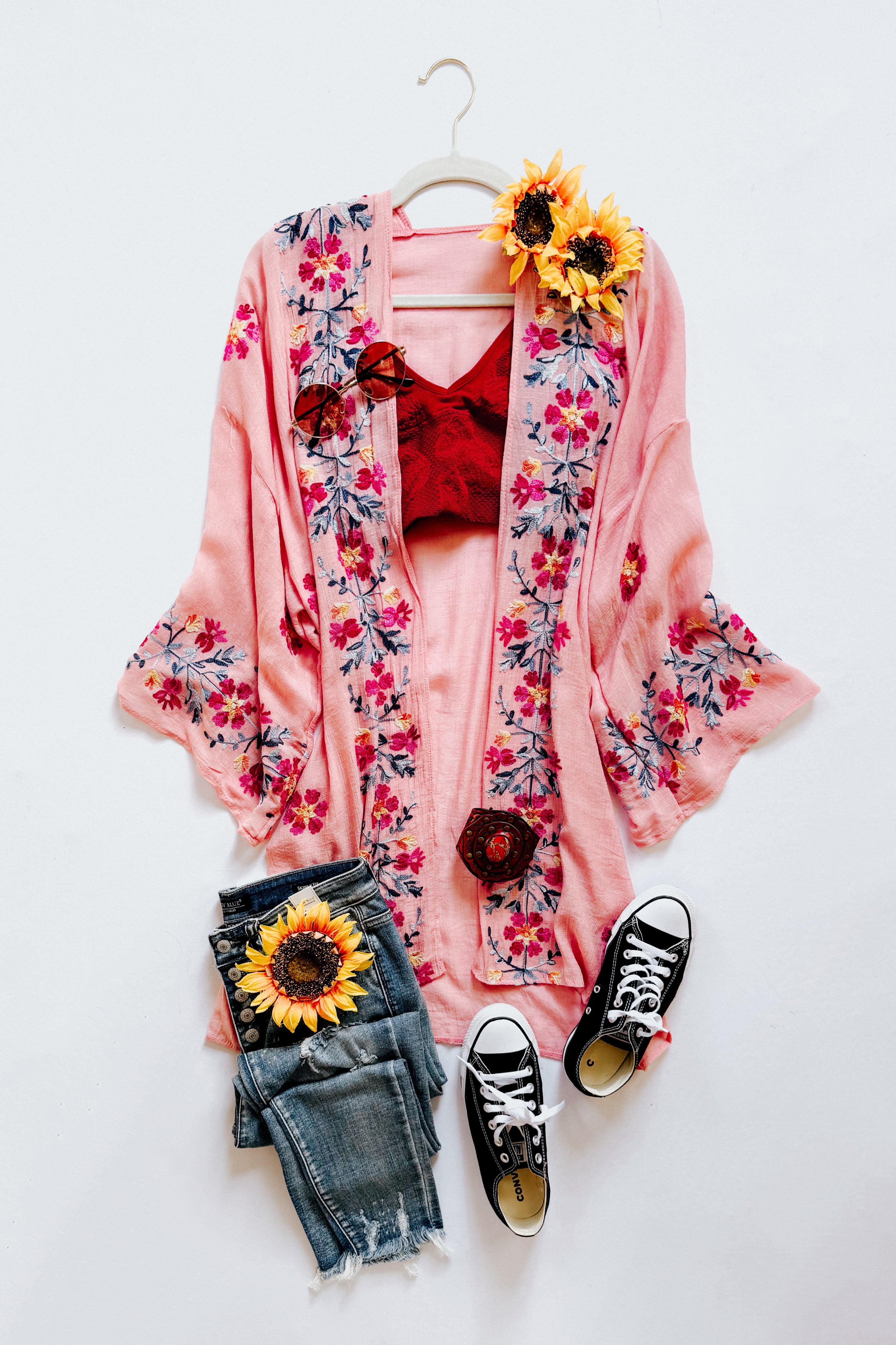 Rose embroidered duster layered over a red top paired with distressed denim shorts and black sneakers styled with sunflowers and sunglasses