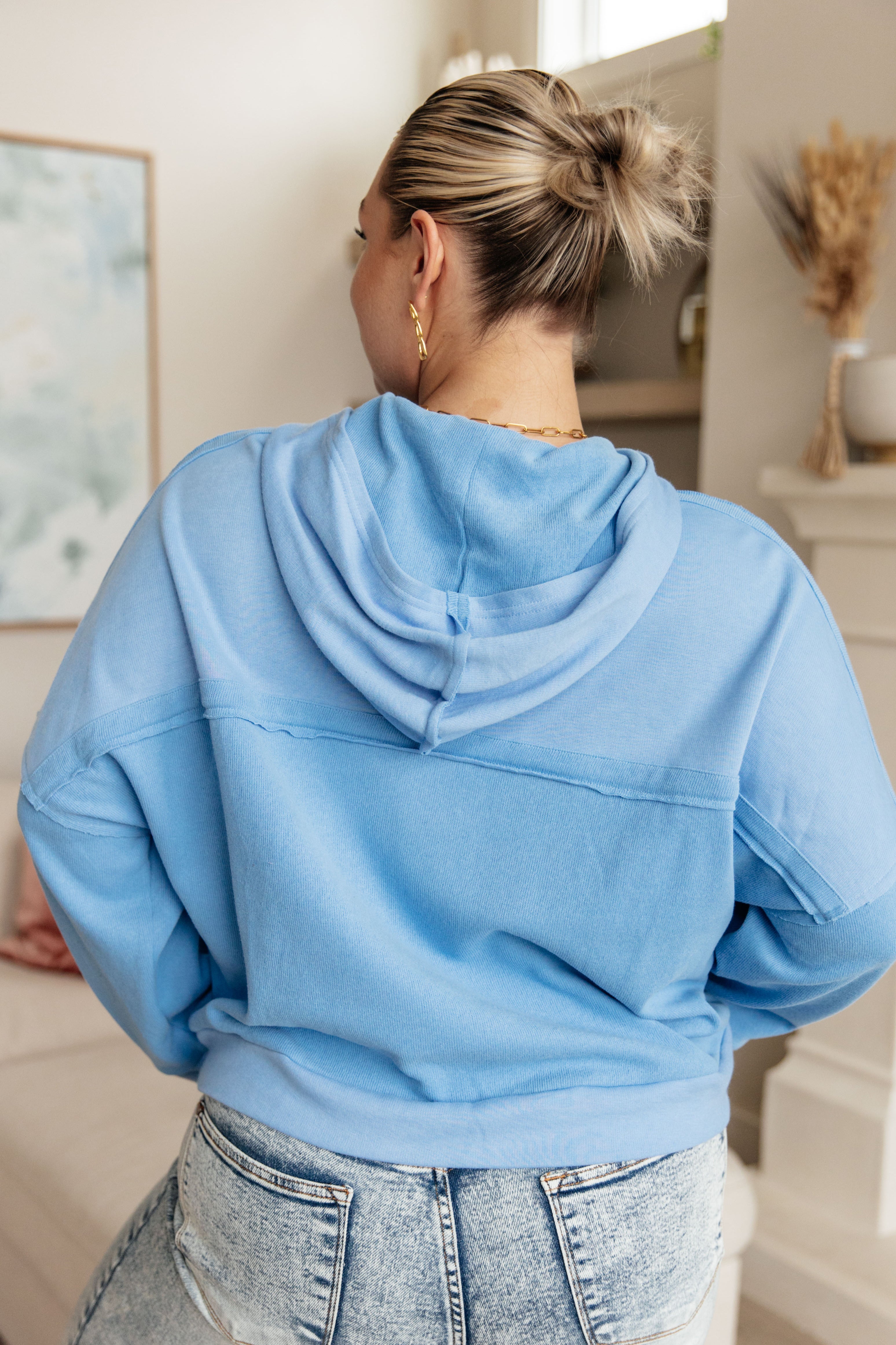 Woman wearing a sky-blue oversized hoodie with dropped shoulders paired with light-wash jeans indoors