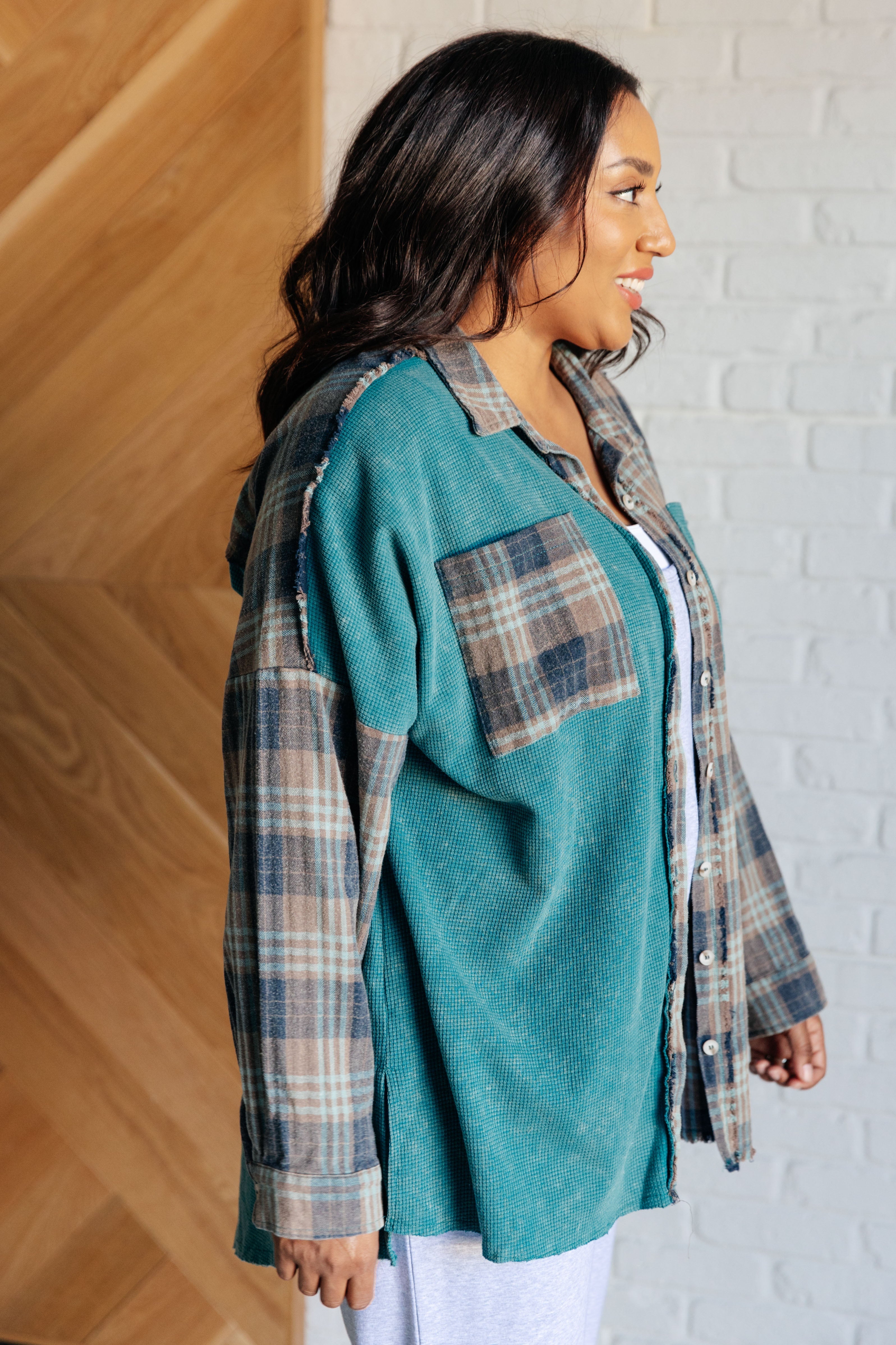 Woman wearing a teal and plaid thermal button-up shirt with relaxed fit indoors smiling in profile view