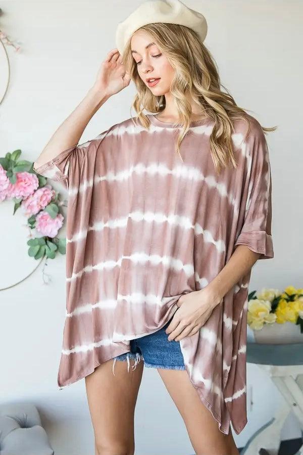 Woman wearing a relaxed fit striped tie dye tunic with rolled sleeves and denim shorts in a bright room setting