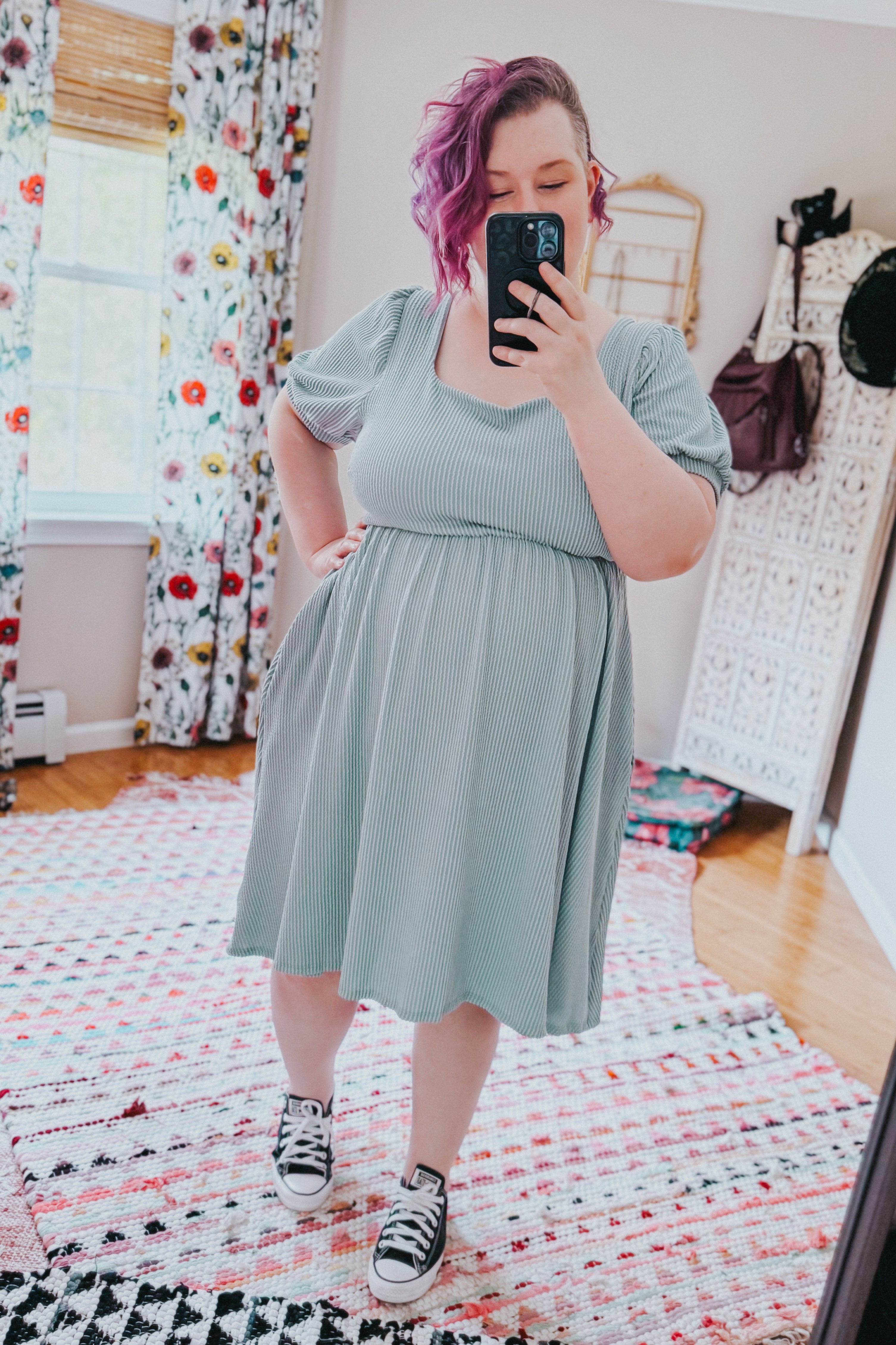 Woman taking a mirror selfie wearing a light sage ribbed knit dress with short puff sleeves and black sneakers