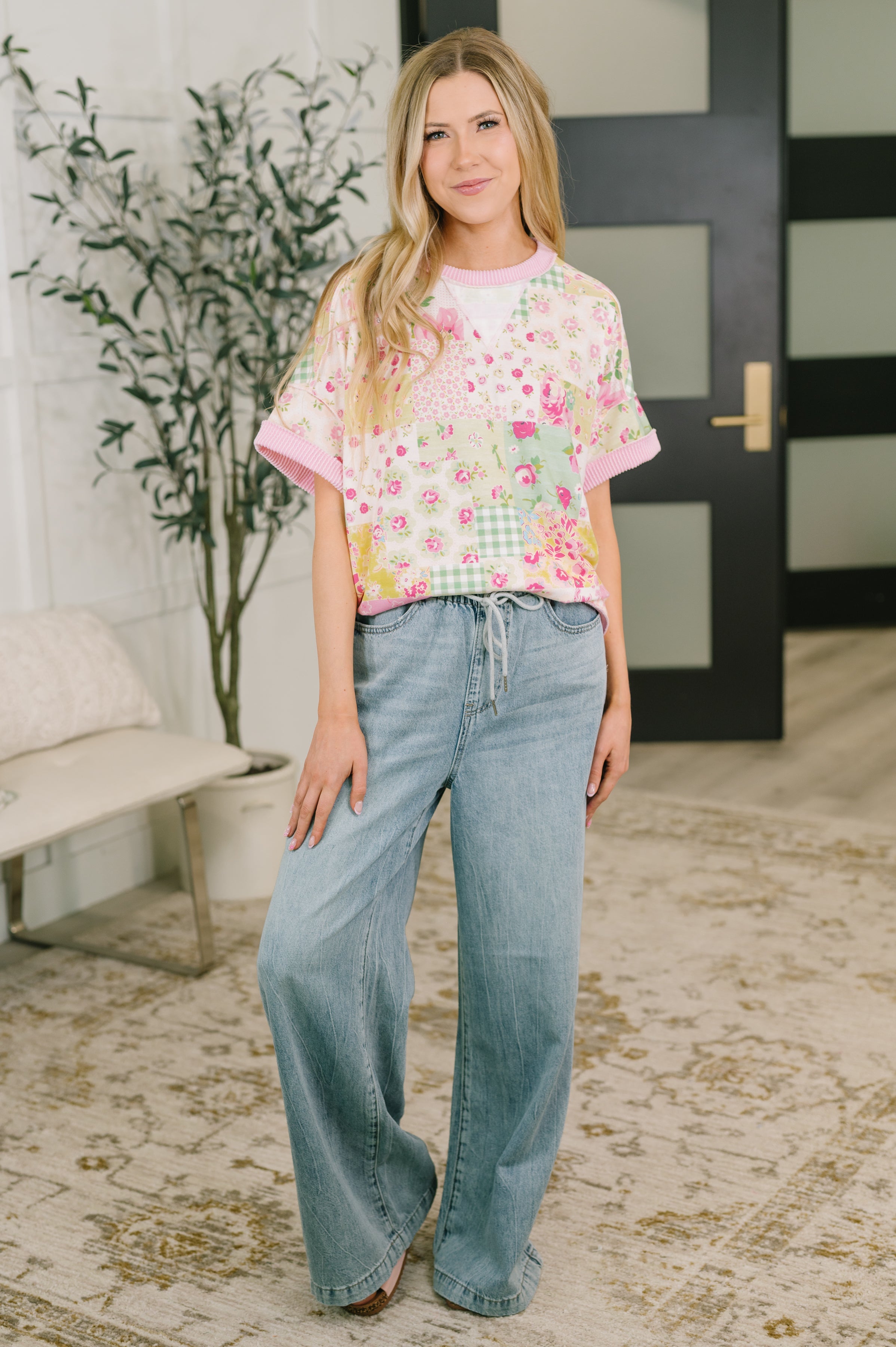 Woman wearing a pink patchwork relaxed tee with rolled sleeves styled with loose denim in an eclectic setting