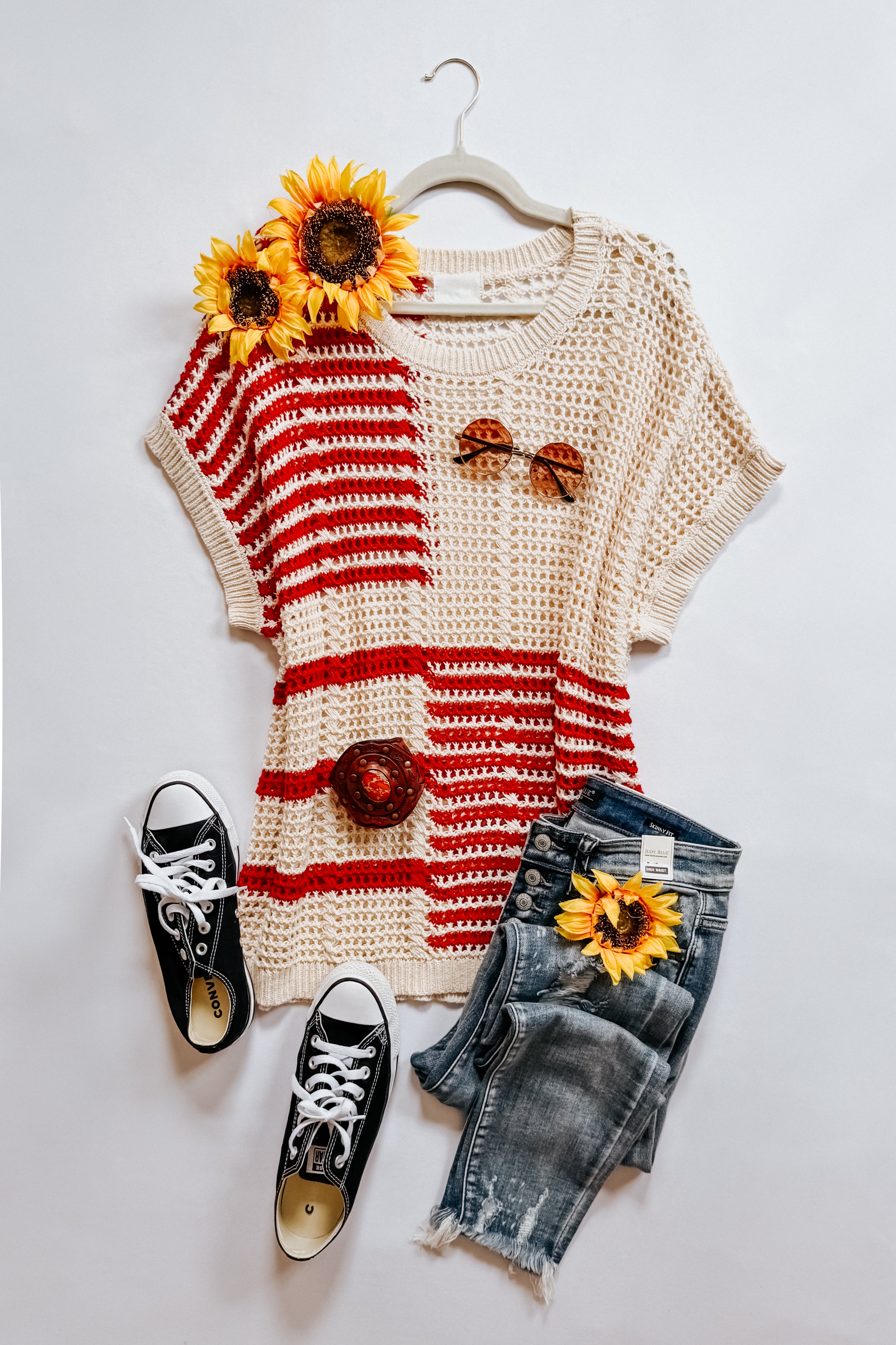 Red striped open knit tee paired with distressed denim shorts, black canvas sneakers, and sunflower accents styled flat lay