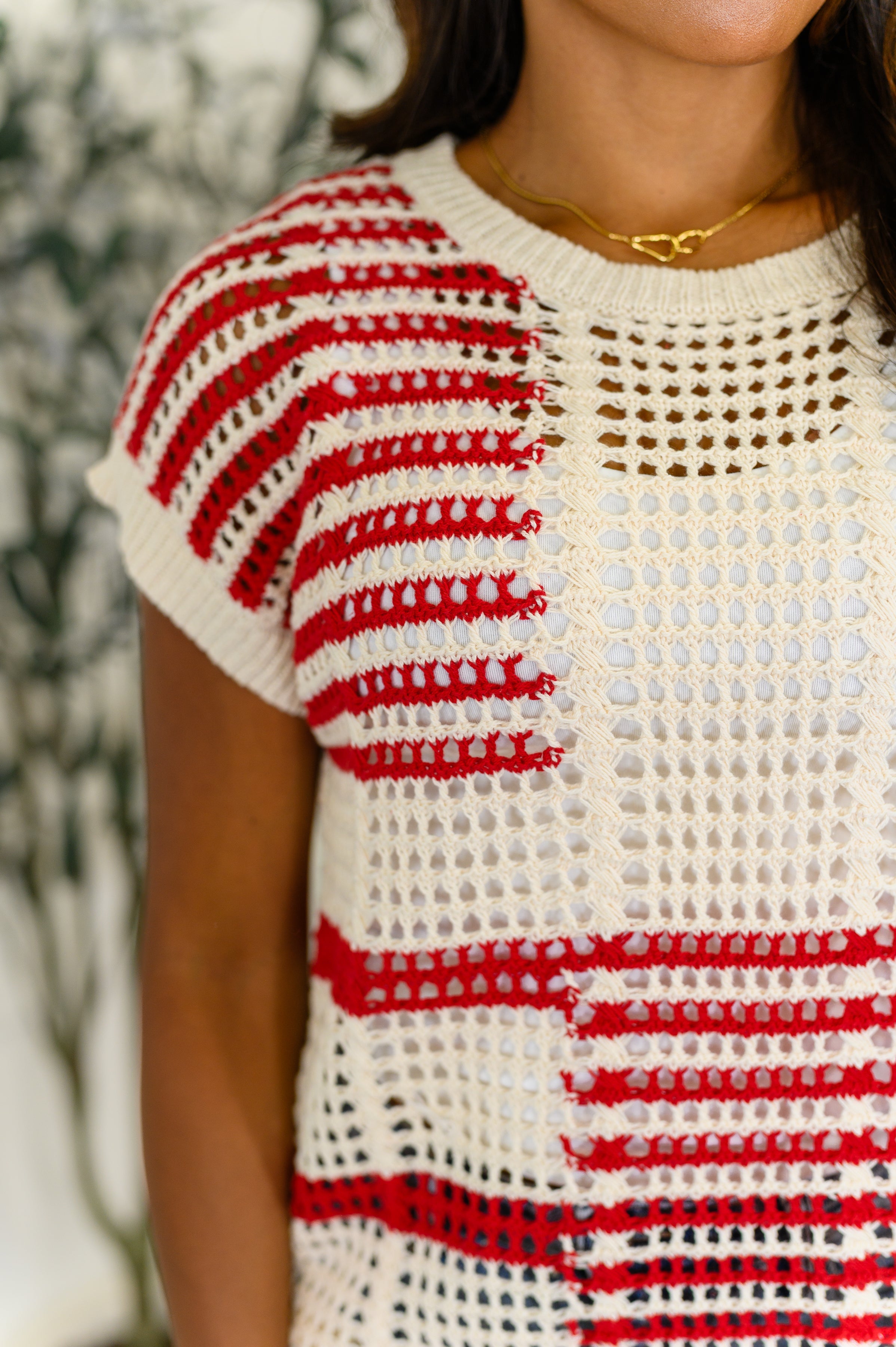 Close-up of a free-spirited red striped net tee with open knit pattern and short sleeves on model