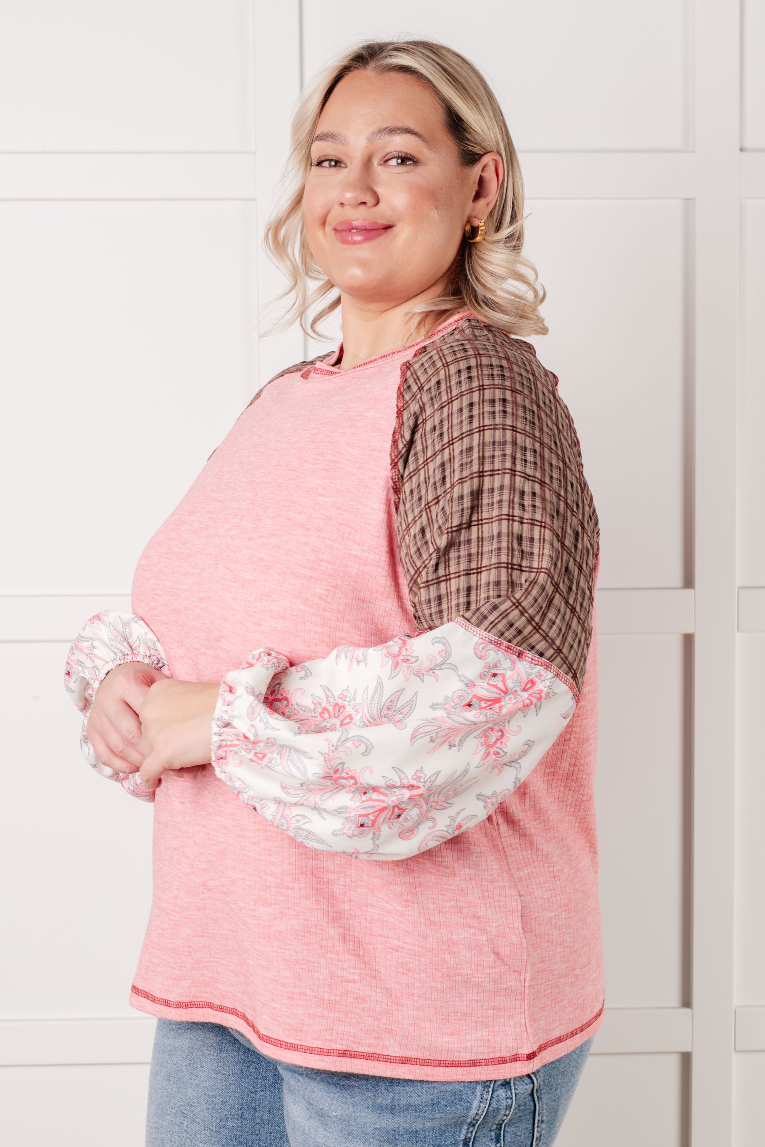 Plus size woman smiling wearing pink Walk for Miles top with brown plaid upper sleeves and floral puffed lower sleeves