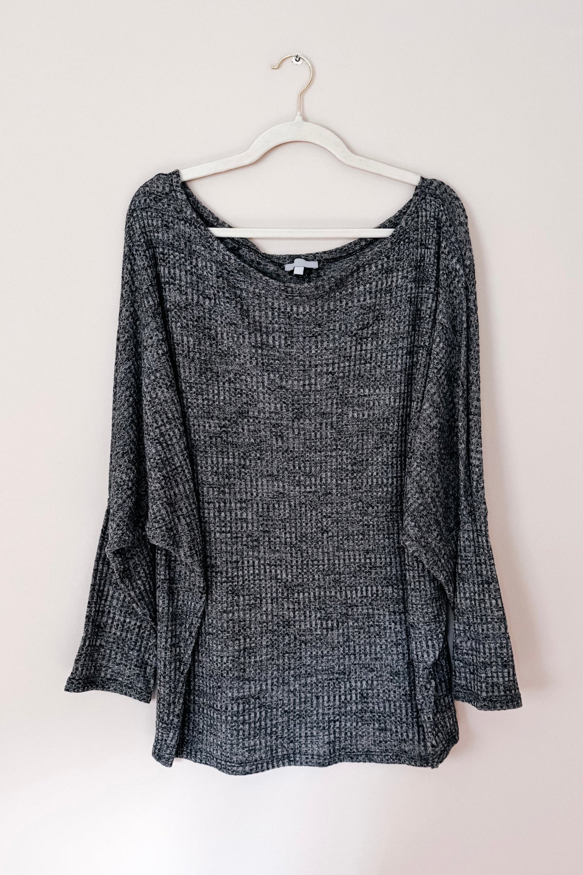 Charcoal ribbed knit top with a wide boat neckline and relaxed dolman sleeves displayed on a hanger