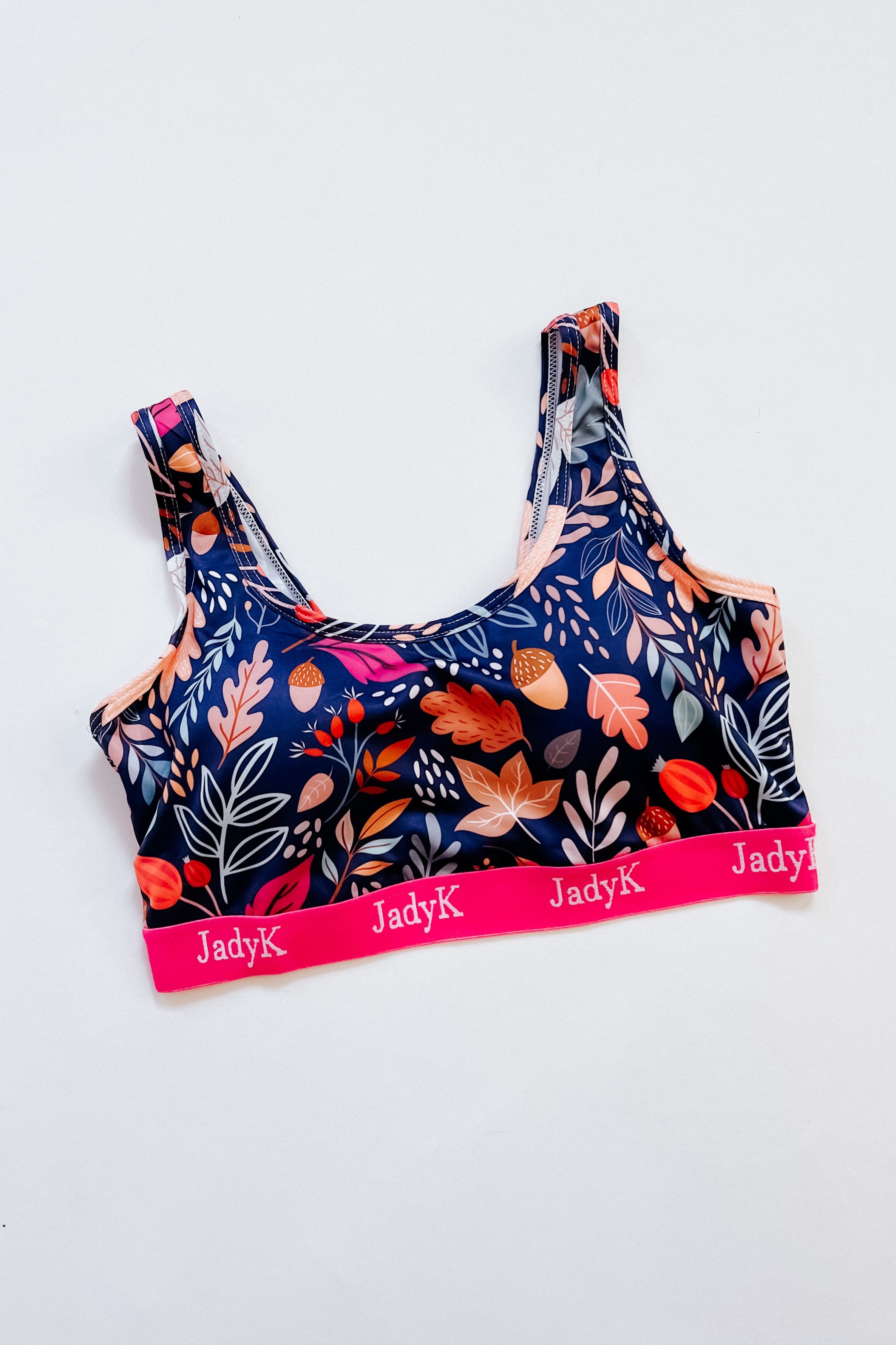 Blue bra with vibrant fall leaf and acorn print and pink elastic band branded with JadyK on white background