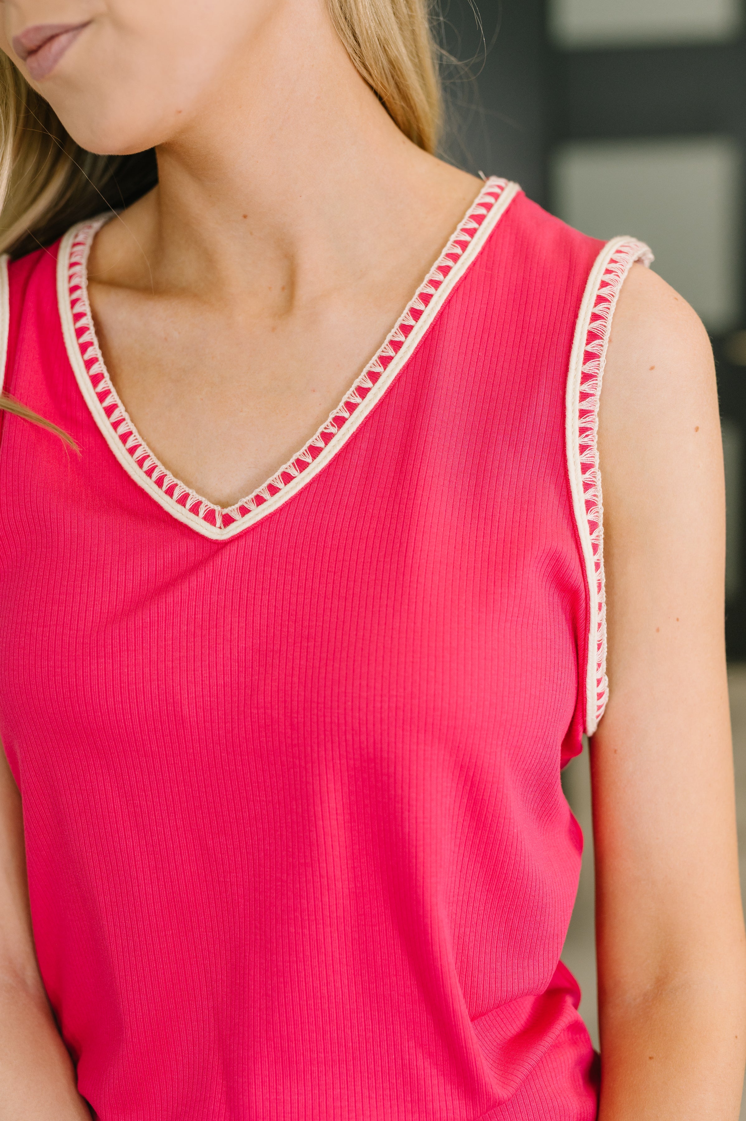 Close-up of hot pink ribbed tank top with V-neck and detailed trim on neckline and armholes worn by woman