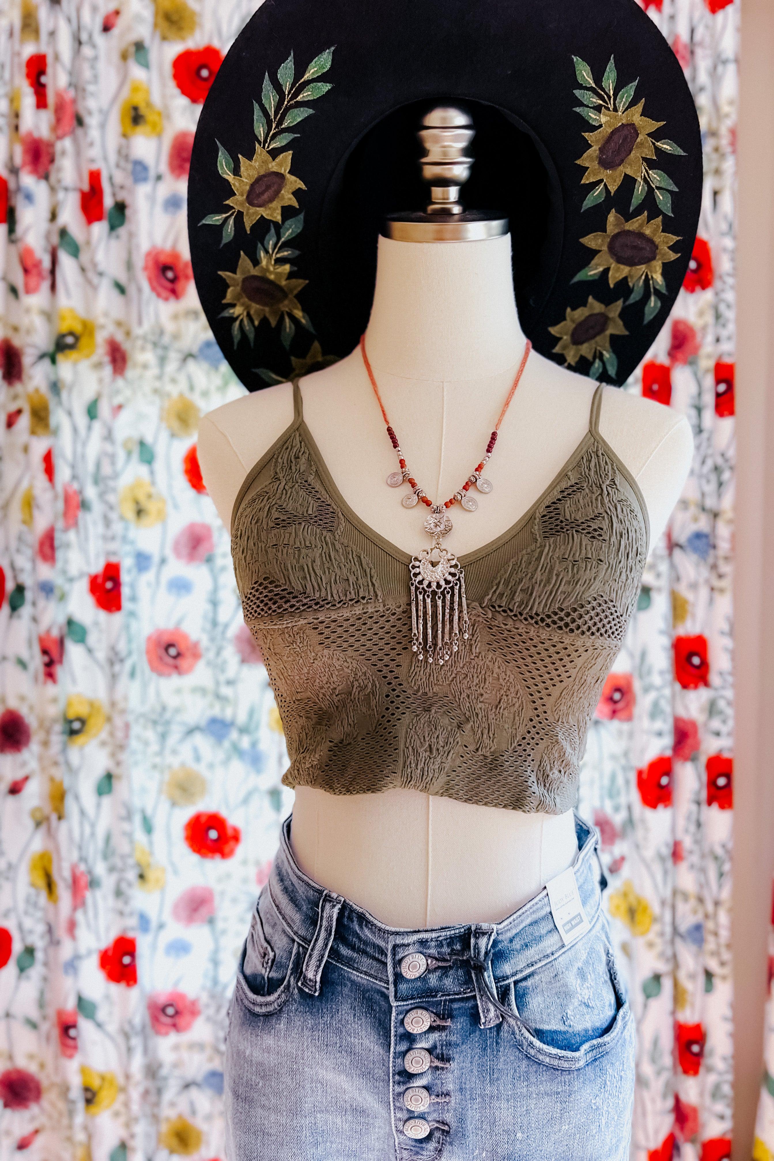 Mannequin dressed in olive textured brami top paired with high-waisted button-fly denim skirt and floral embroidered hat
