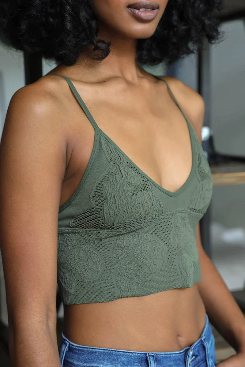 Woman modeling olive textured brami with slim straps and seamless design paired with blue jeans indoors