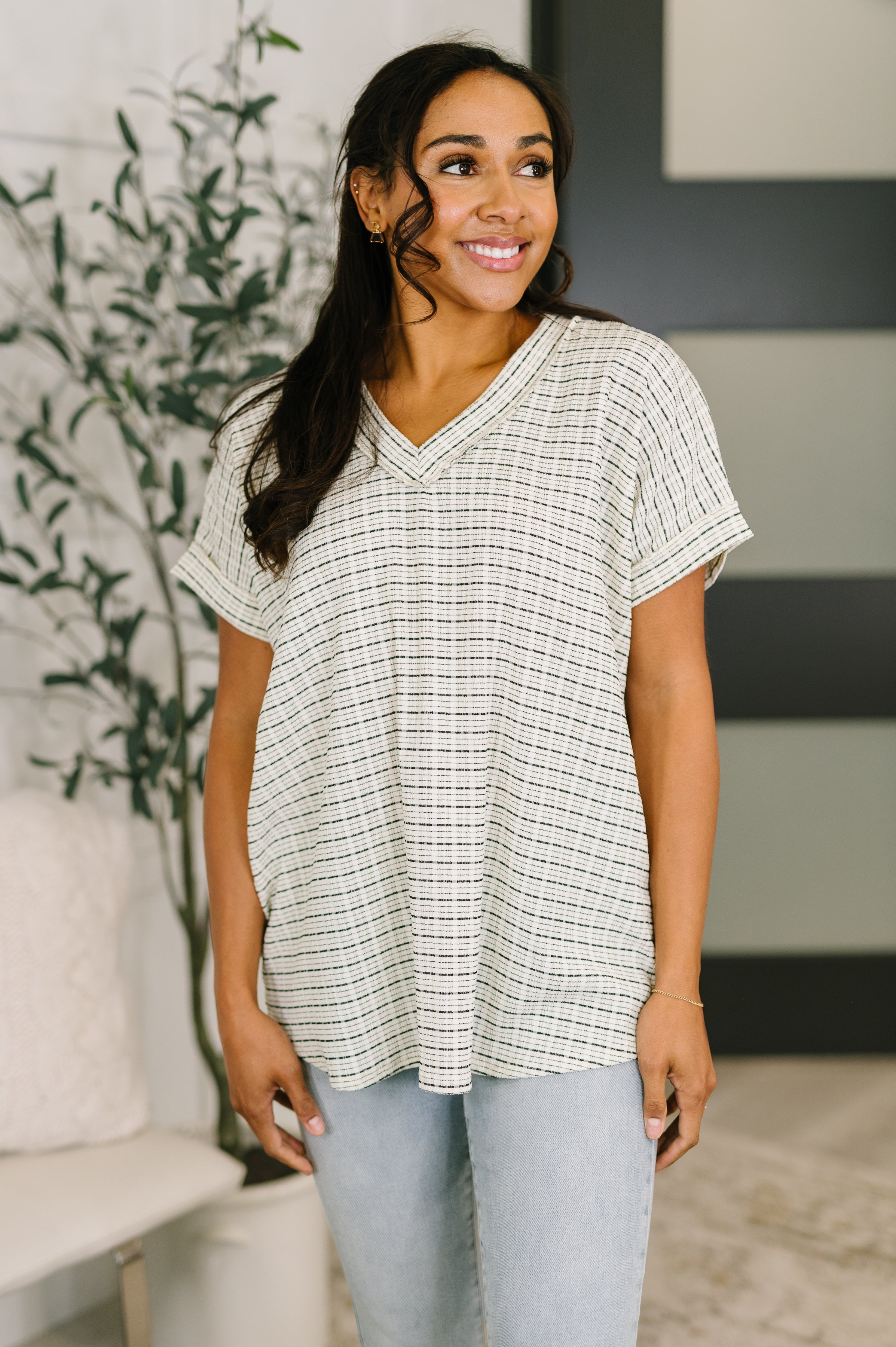 Woman wearing a cream textured knit V-neck top with short cuffed sleeves in a relaxed, eclectic size-inclusive style