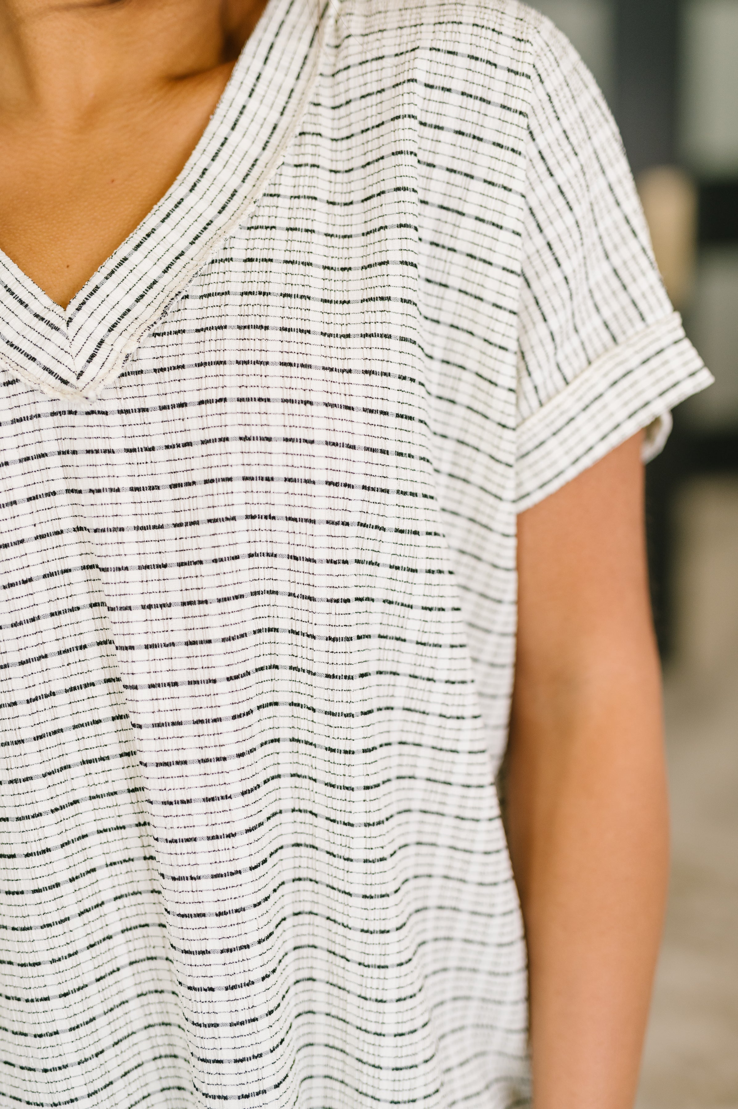 Close-up of cream textured knit V-neck top with short rolled sleeves in an eclectic, size-inclusive style