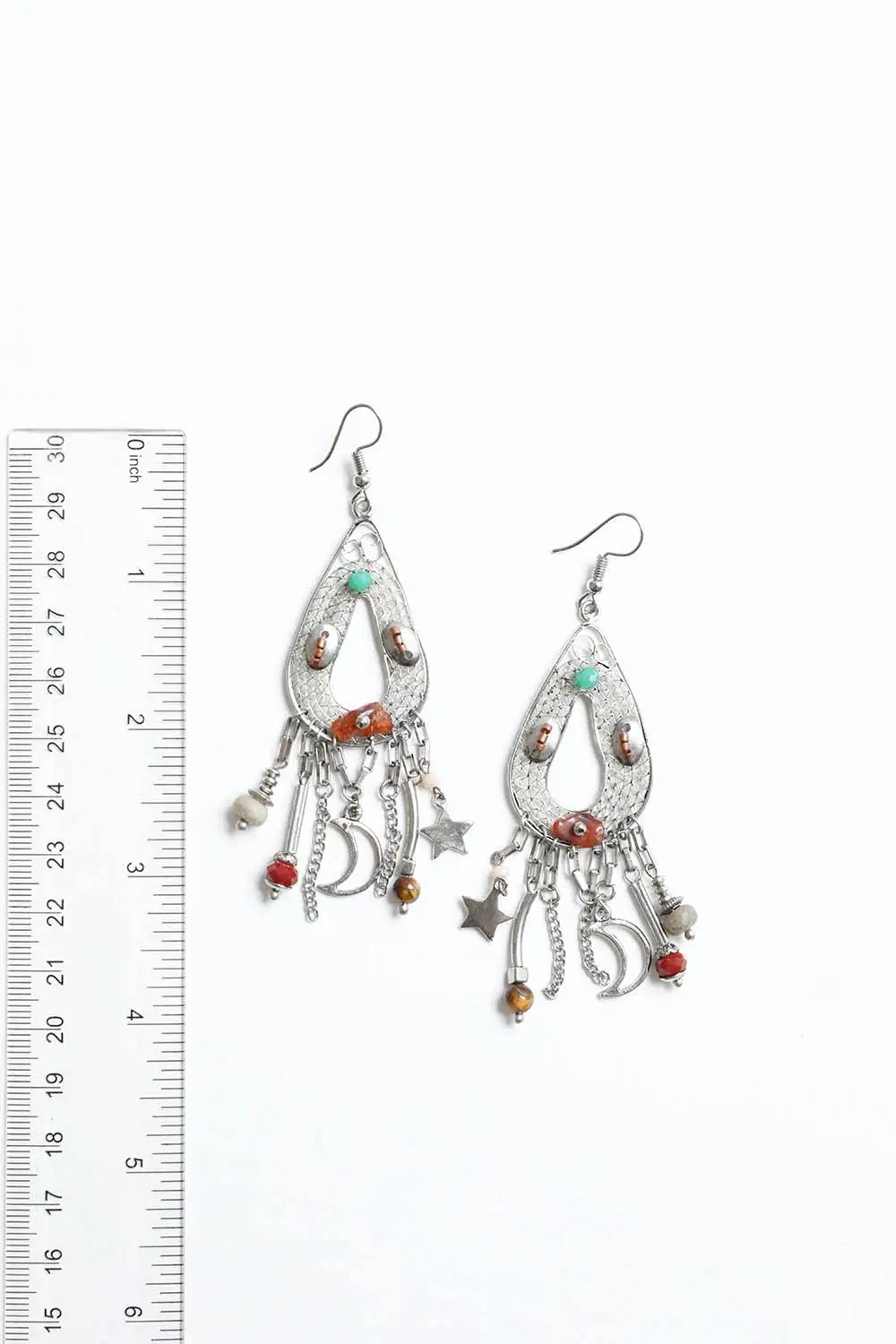 Silver teardrop earrings with moon, star charms and multicolored beads shown next to a ruler on white background