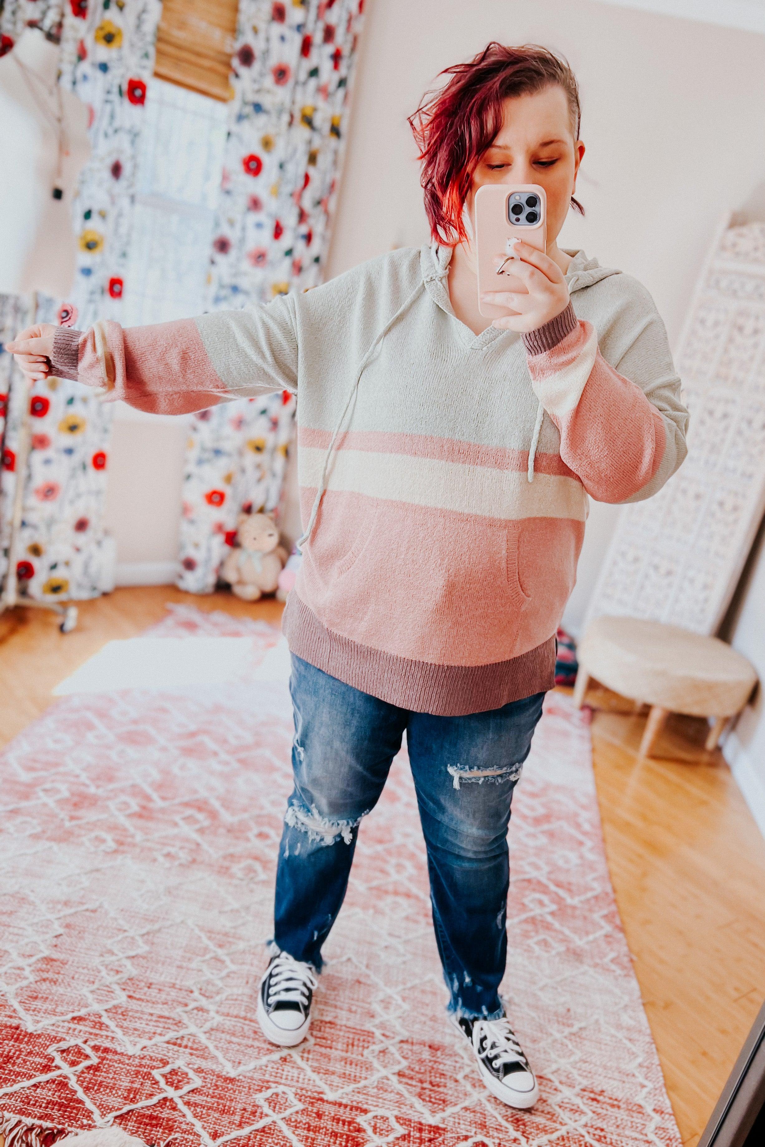 Woman taking mirror selfie wearing pastel striped Boy Problem Spring Hoodie with ripped jeans and black sneakers