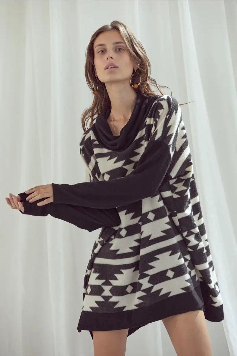 Woman wearing black and white geometric print cowl neck pullover with long sleeves against white backdrop