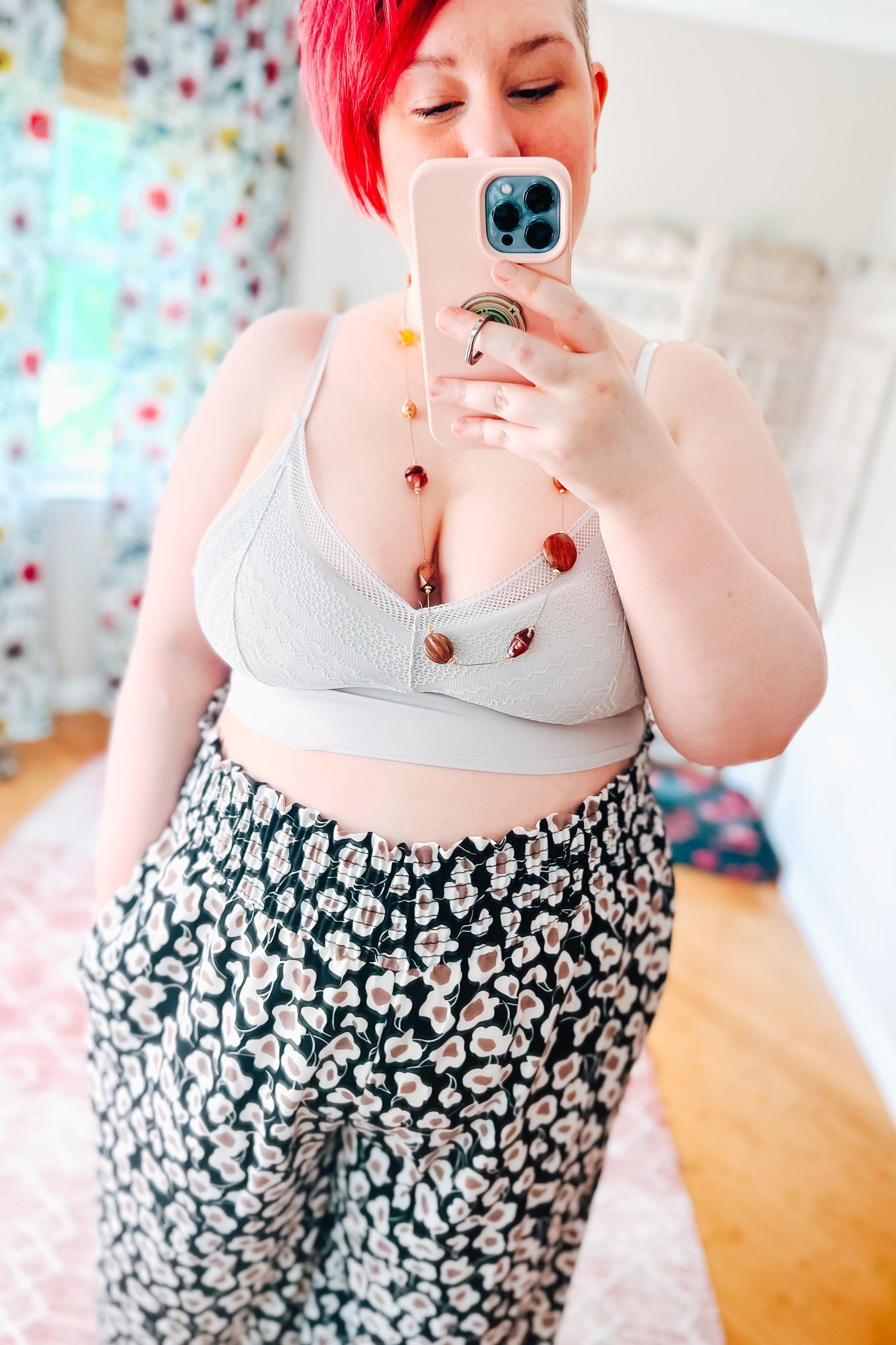 Plus size model wearing silver textured bralette paired with floral wide-leg pants taking a mirror selfie