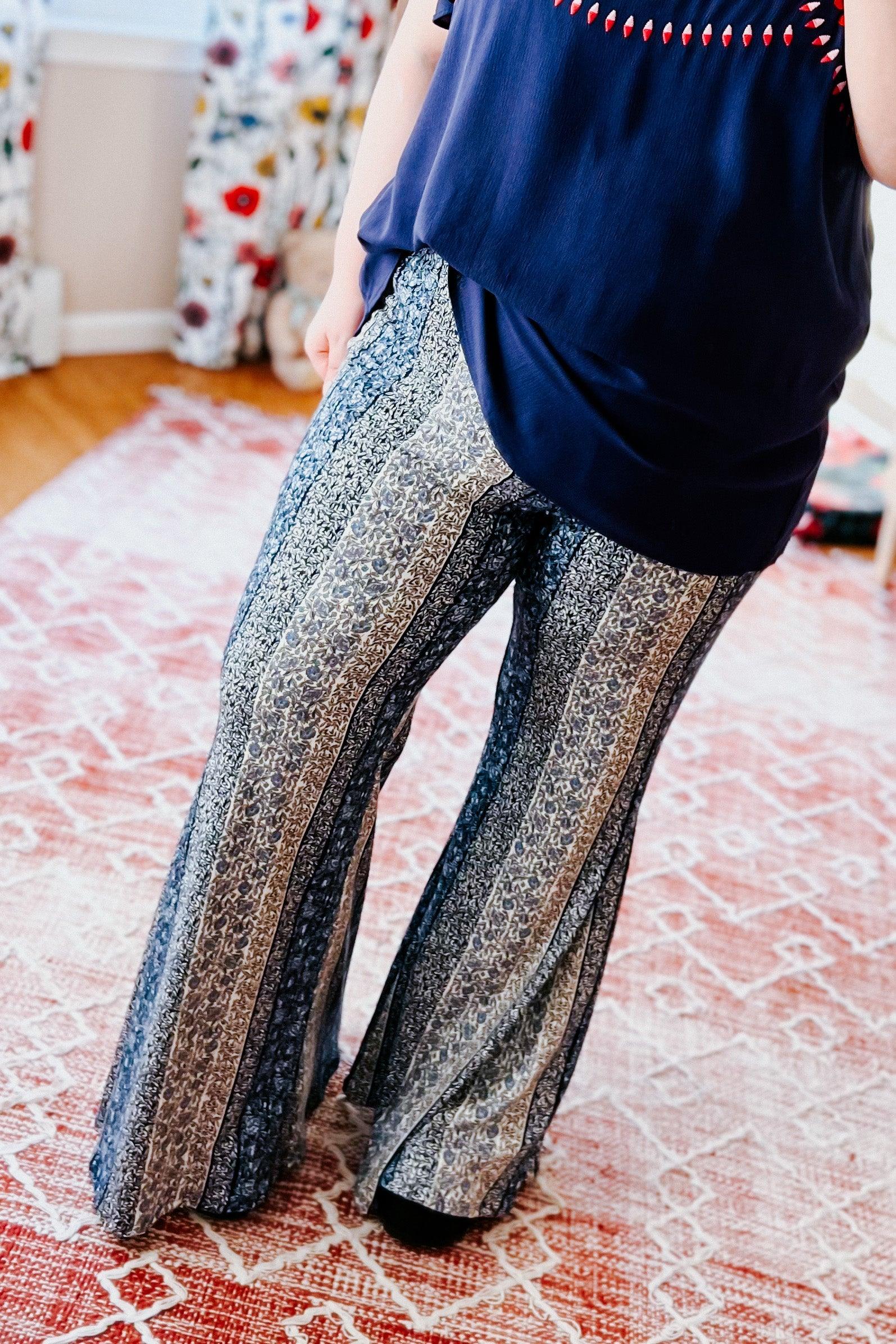 Fleetwood Floral Bell Bottoms in navy with vertical paisley and abstract striped patterns, styled with a loose navy top in a bright room with patterned curtains.