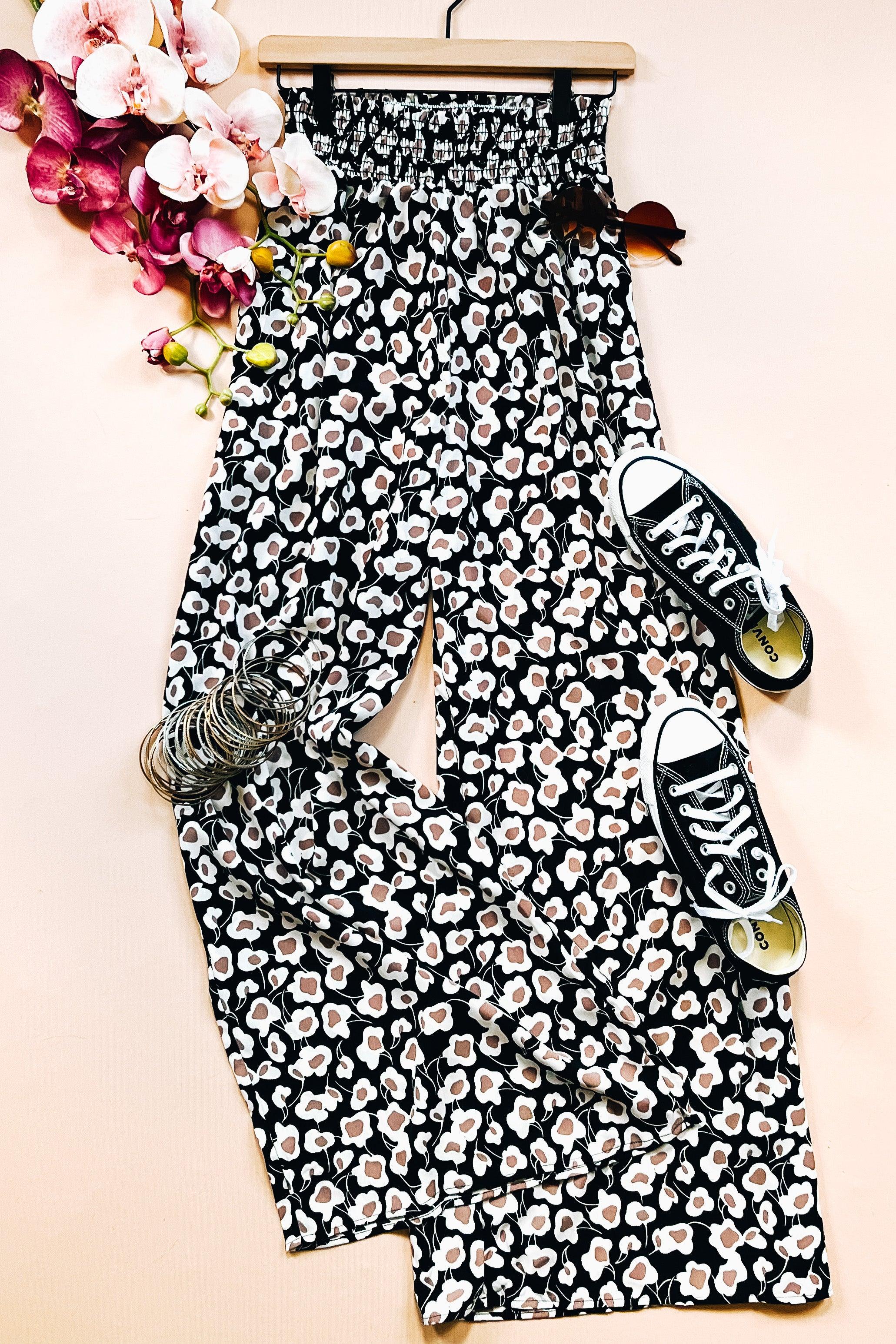 Flowers In Your Hair Retro Vintage Print Smocked Pants laid flat with black sneakers and floral accents on pale background