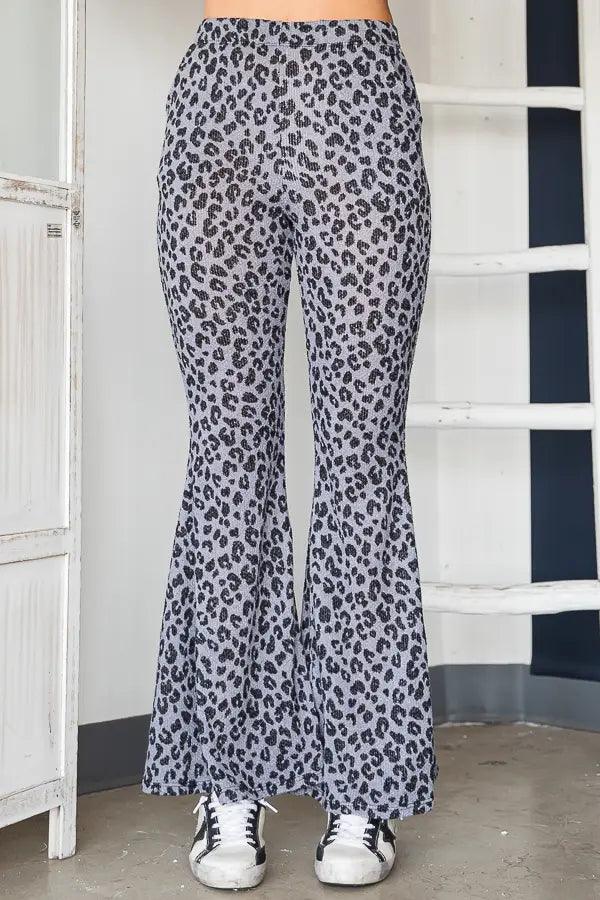 Woman wearing high-waisted bell bottom pants with blue leopard print pattern and casual white sneakers indoors