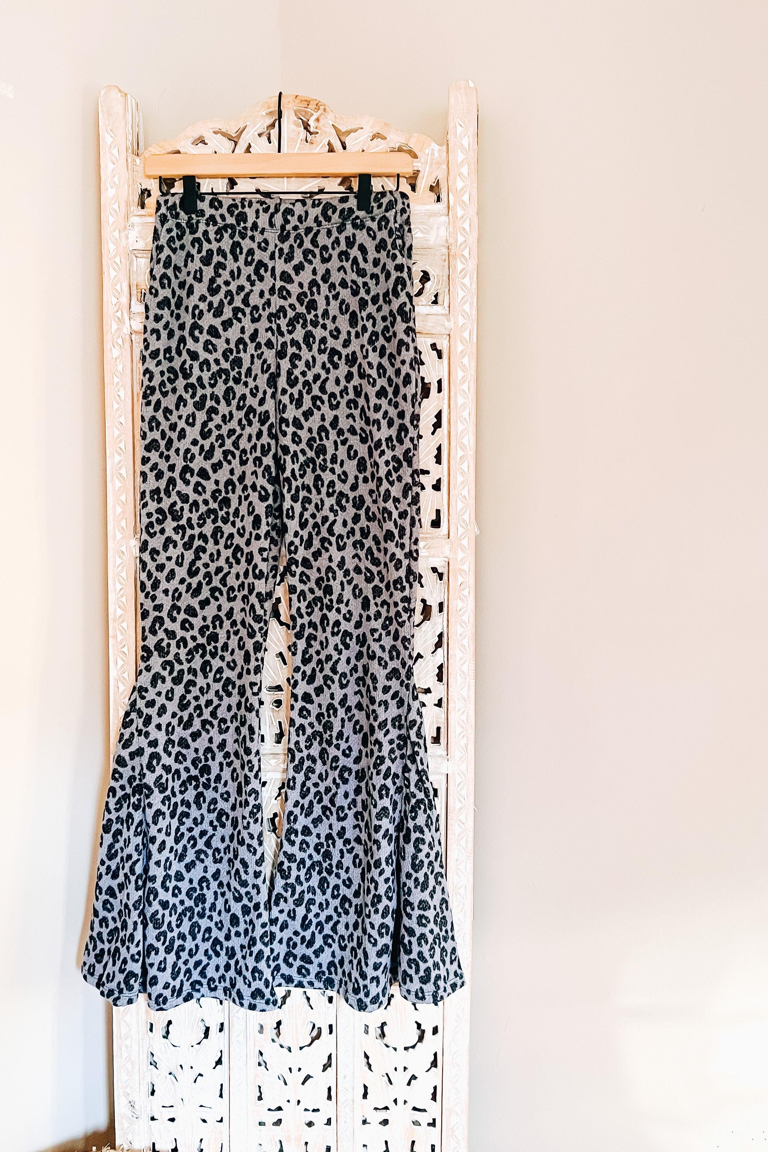 Blue bell bottoms with black leopard print hanging against carved white wooden screen