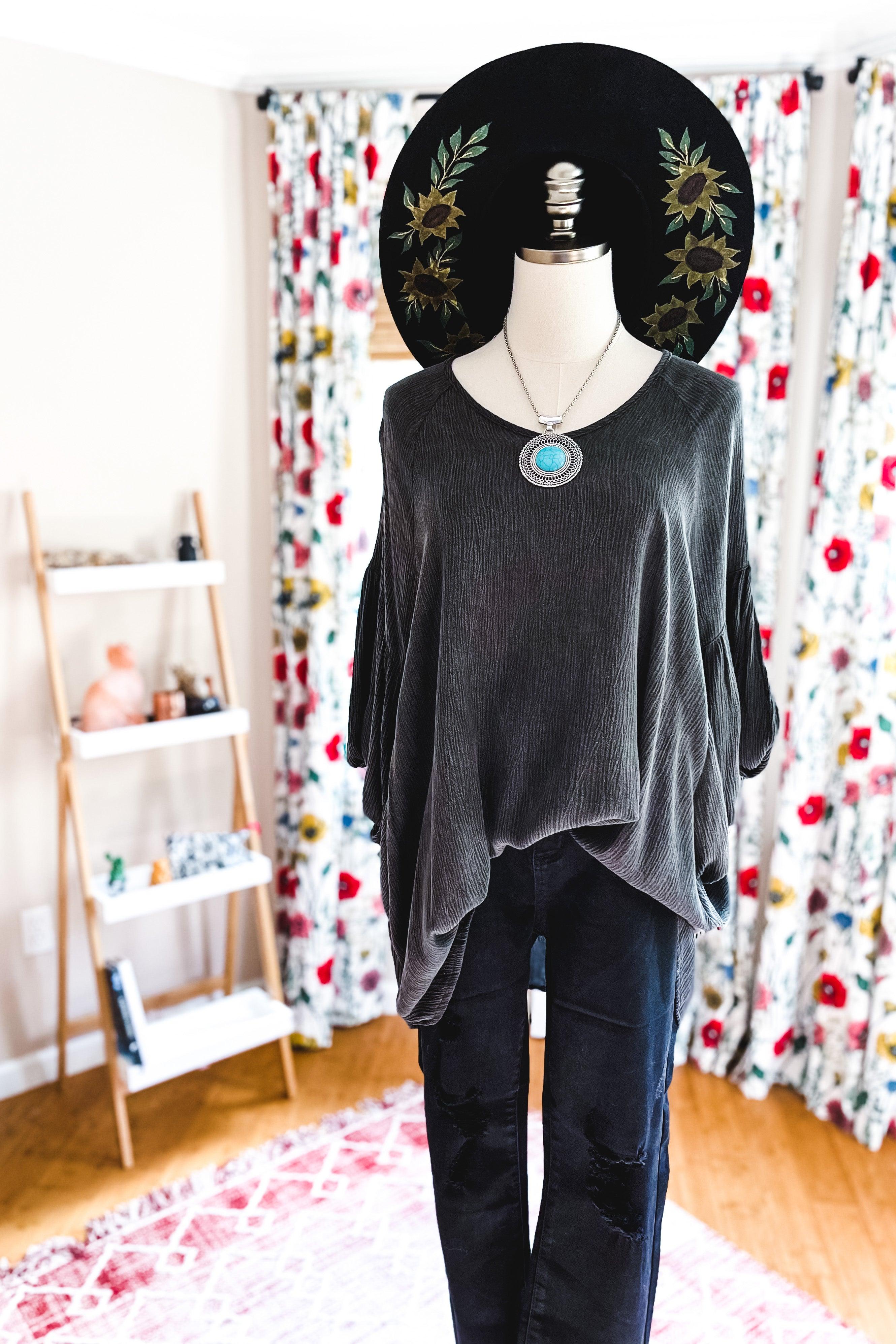 Charcoal textured loose tunic with draped silhouette styled with black distressed pants and statement turquoise necklace on mannequin