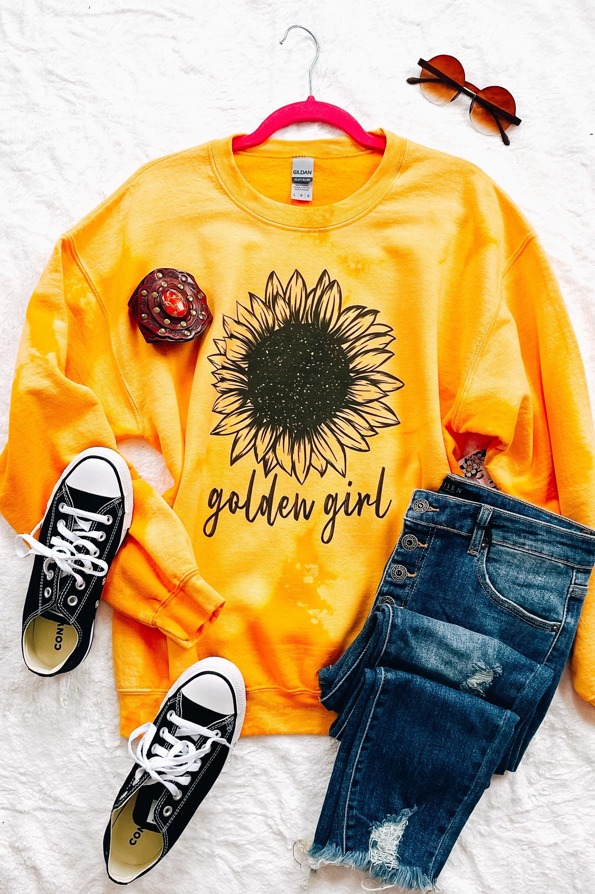 Yellow bleached pullover with black sunflower graphic and golden girl text styled with denim shorts and black sneakers