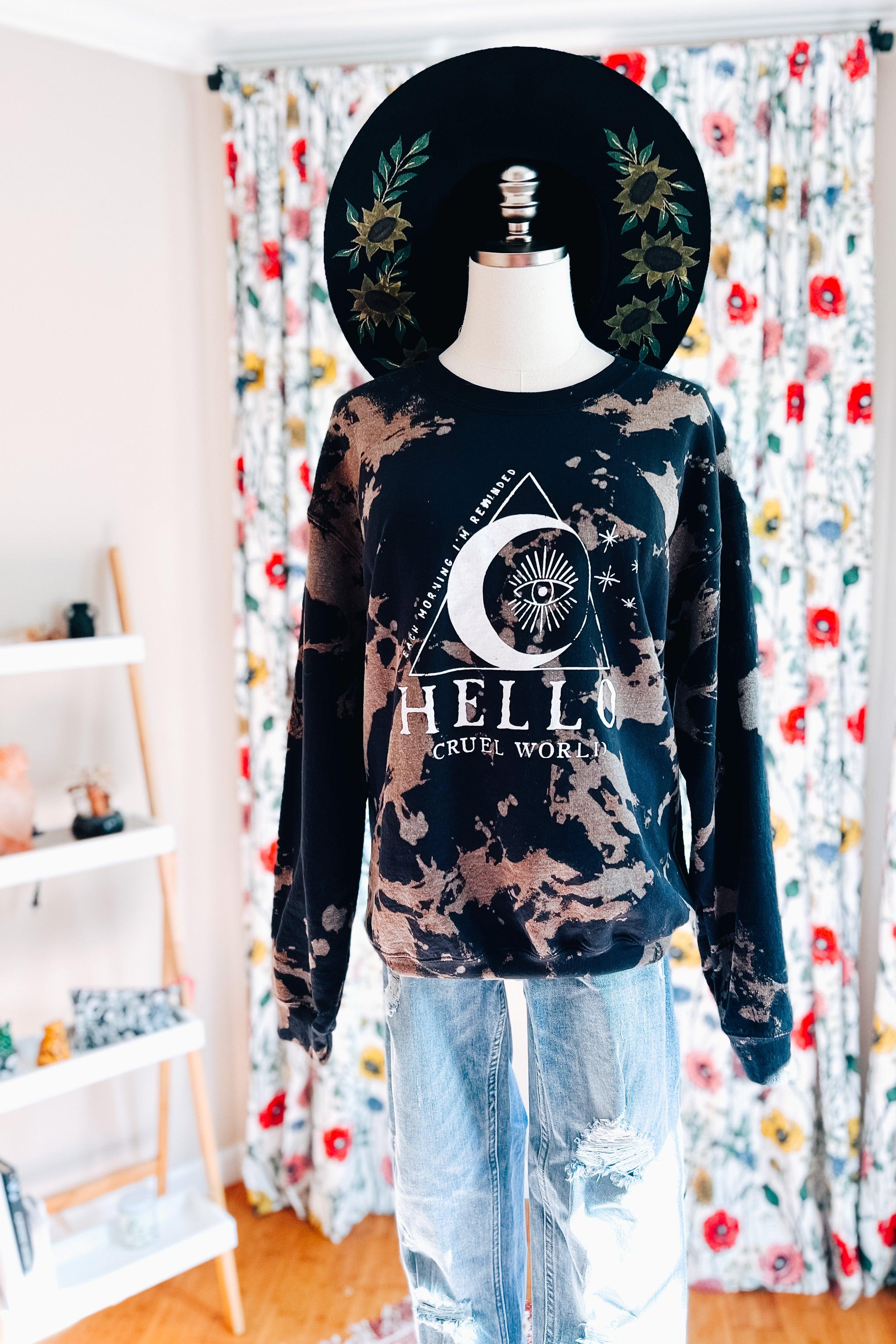 Black Hello Cruel World sweatshirt with bleached pattern and celestial eye graphic on mannequin indoors